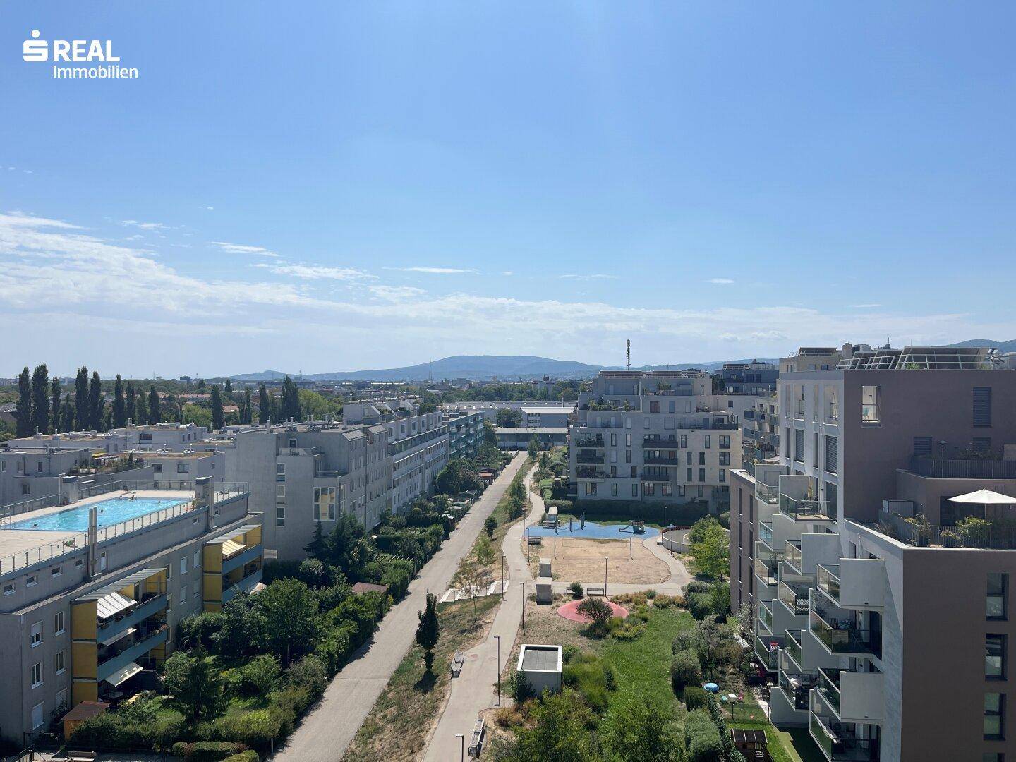 Weitläufiger Blick über die moderne Wohnanlage mit Grünflächen und Spielplatz.