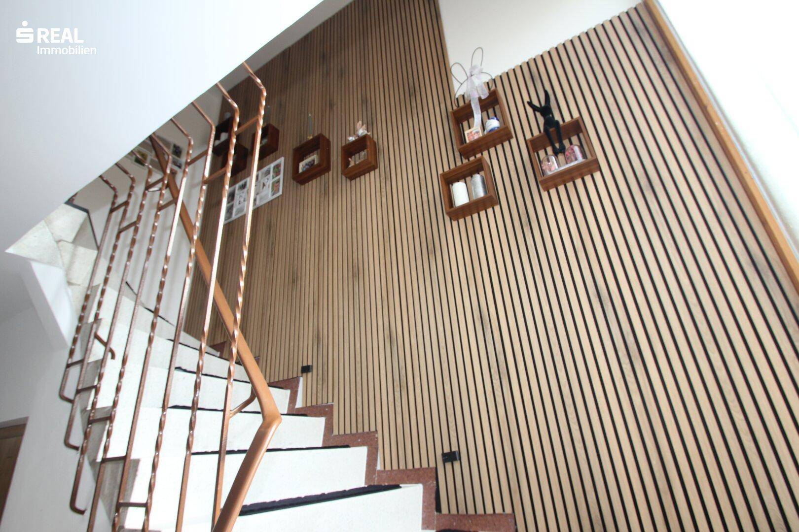 Treppenhaus mit moderner Holzvertäfelung und dekorativen Elementen an der Wand.