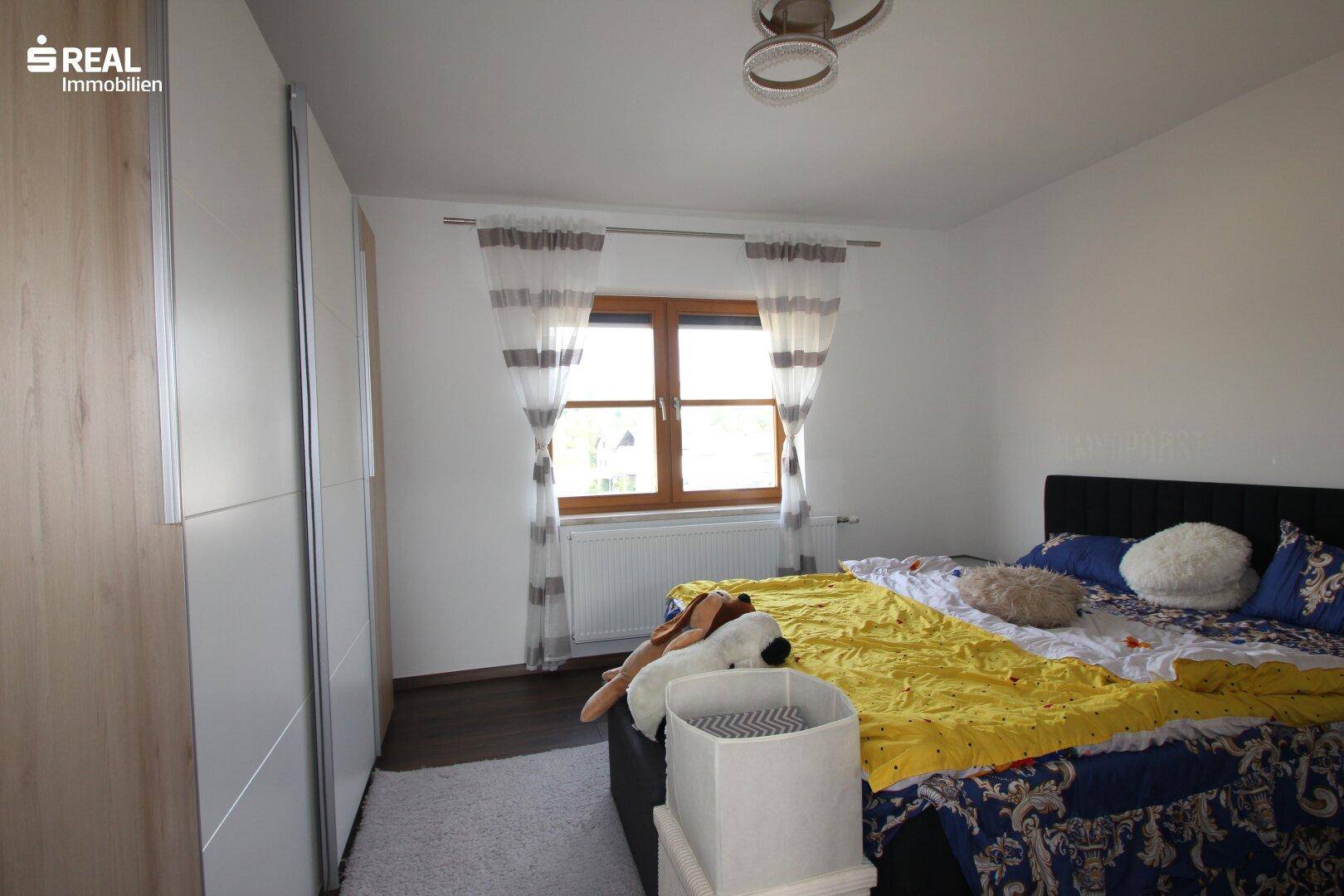 Gemütliches Schlafzimmer mit Doppelbett, Kleiderschrank und hellem Teppich.