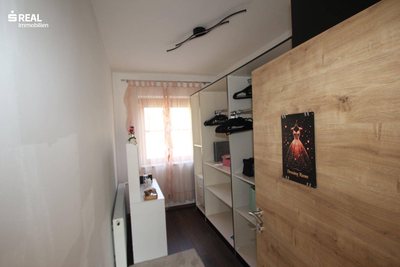 Praktischer begehbarer Kleiderschrank mit Regalen und Fenster.