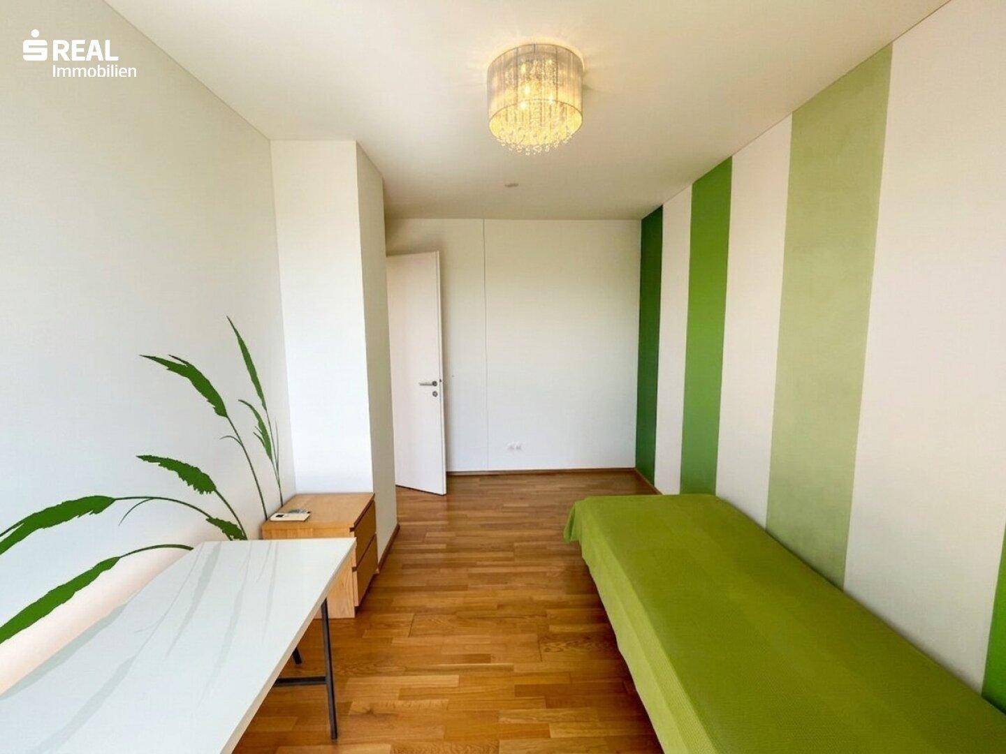 Helles Schlafzimmer mit Holzboden und grünen Akzentwänden, ideal für Kinder.