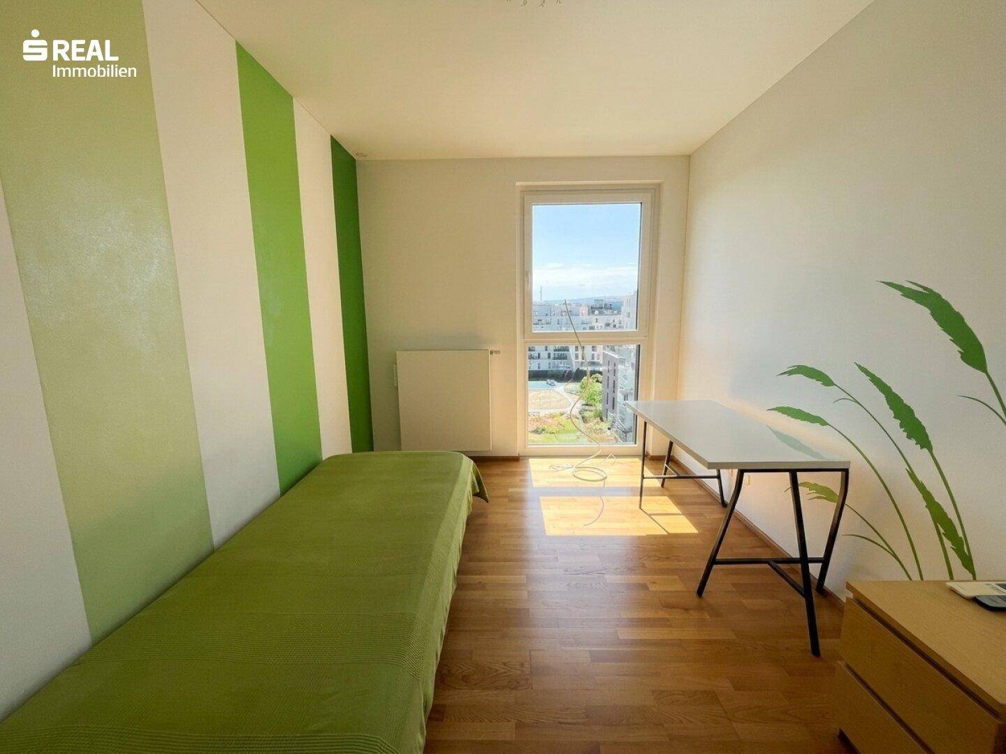 Kinderzimmer mit großem Fenster, Holzboden und grünen Streifen an der Wand.