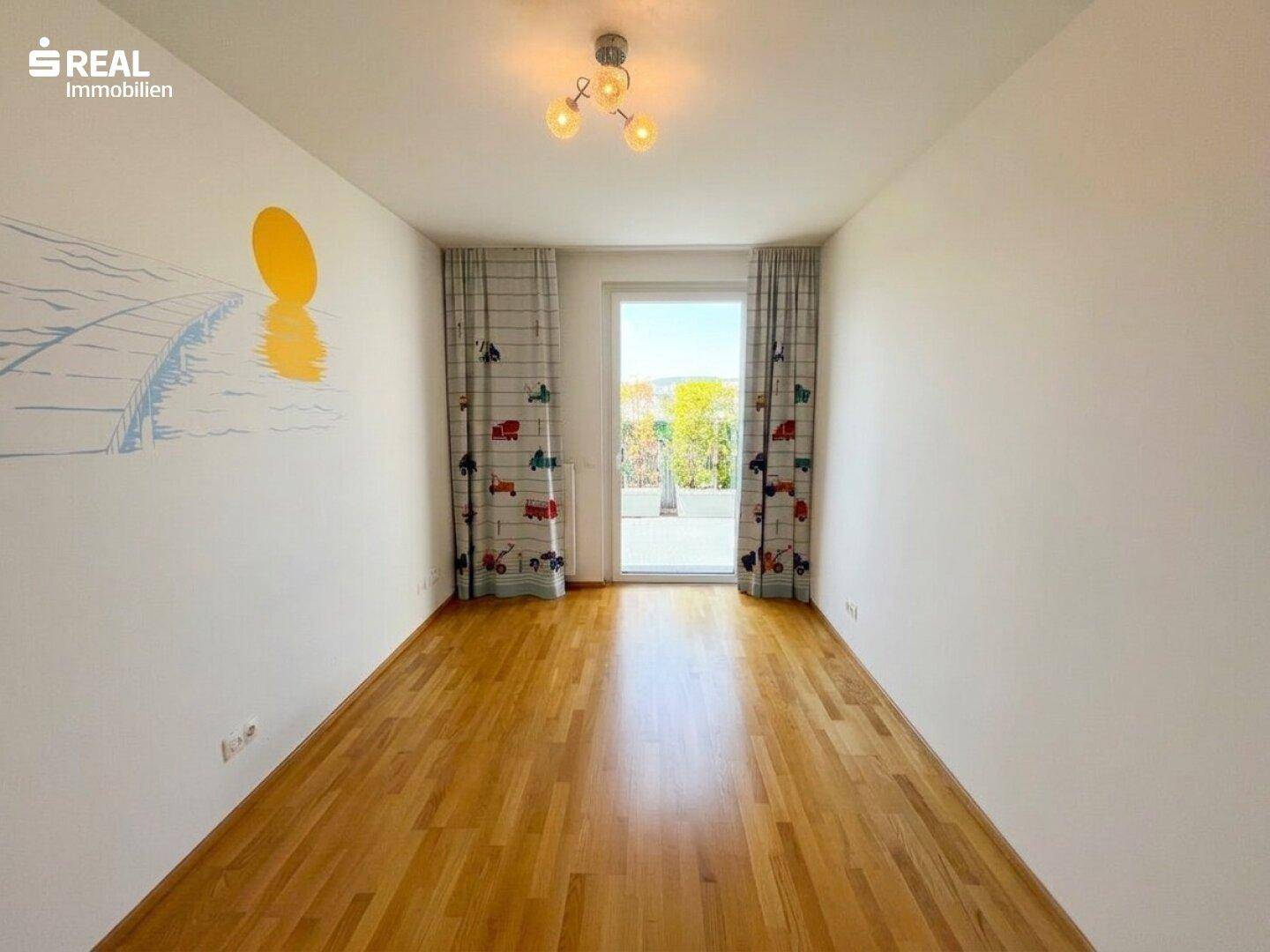 Helles Kinderzimmer mit Holzboden, Zugang zur Terrasse und spielerischen Vorhängen.