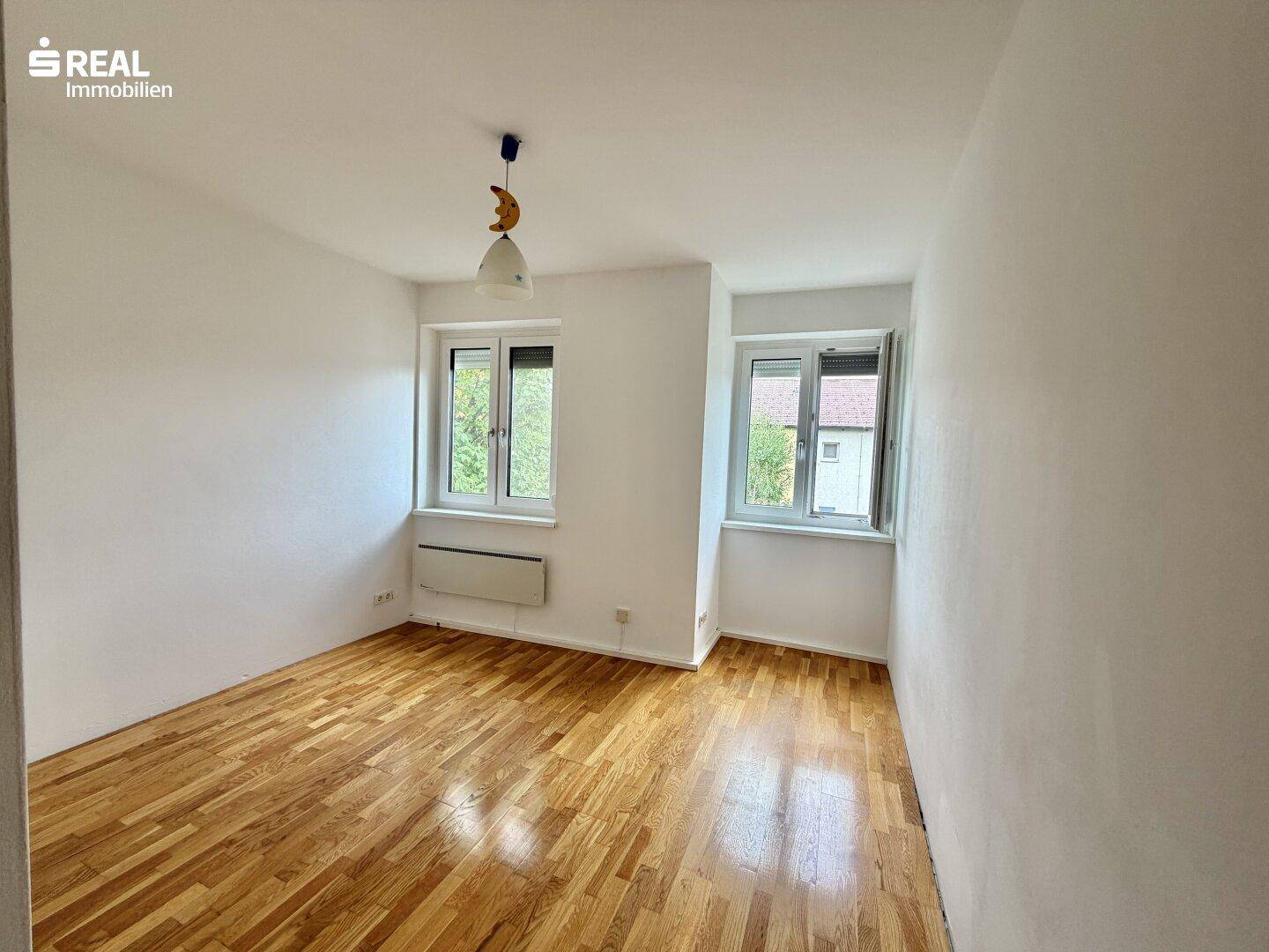 Helles Zimmer mit Parkettboden und zwei Fenstern, ideal als Schlaf- oder Arbeitszimmer nutzbar.