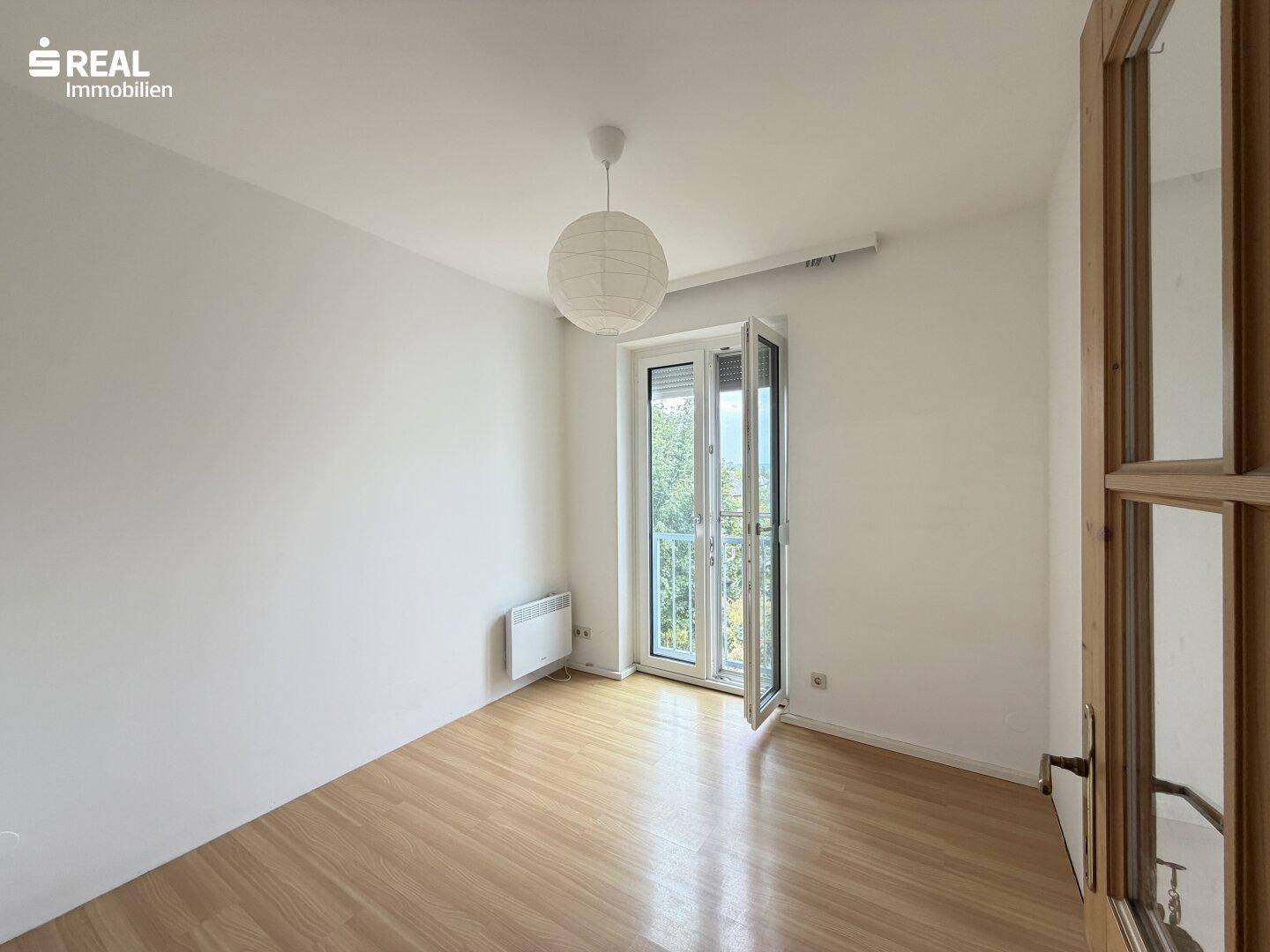 Lichtdurchflutetes Zimmer mit Korkboden und einem französischen Balkon, ideal für ein Schlafzimmer.