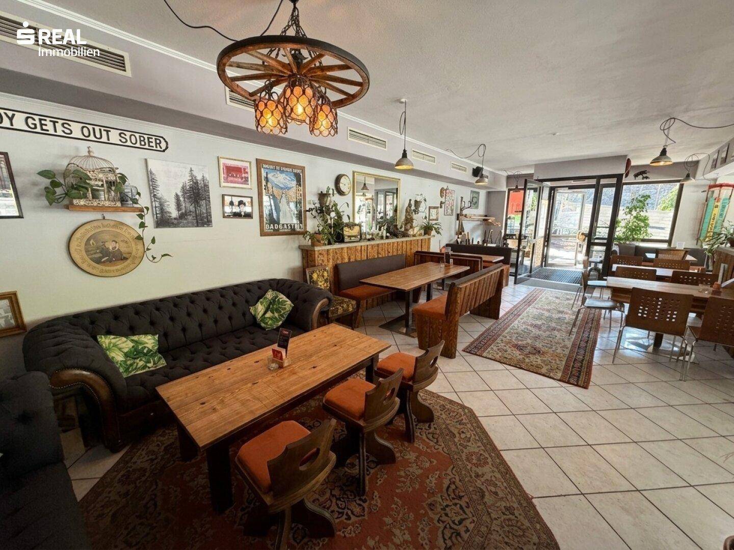 Gemütlicher Loungebereich im Gastraum mit Sofa, Holztischen und dekorativen Elementen, ideal zum Entspannen.