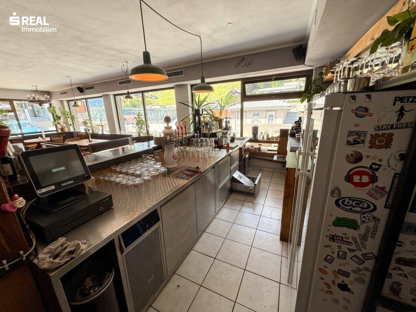 Funktionale Bartheke mit Kassensystem, Gläsern und Kühlschrank, bereit für den Service.