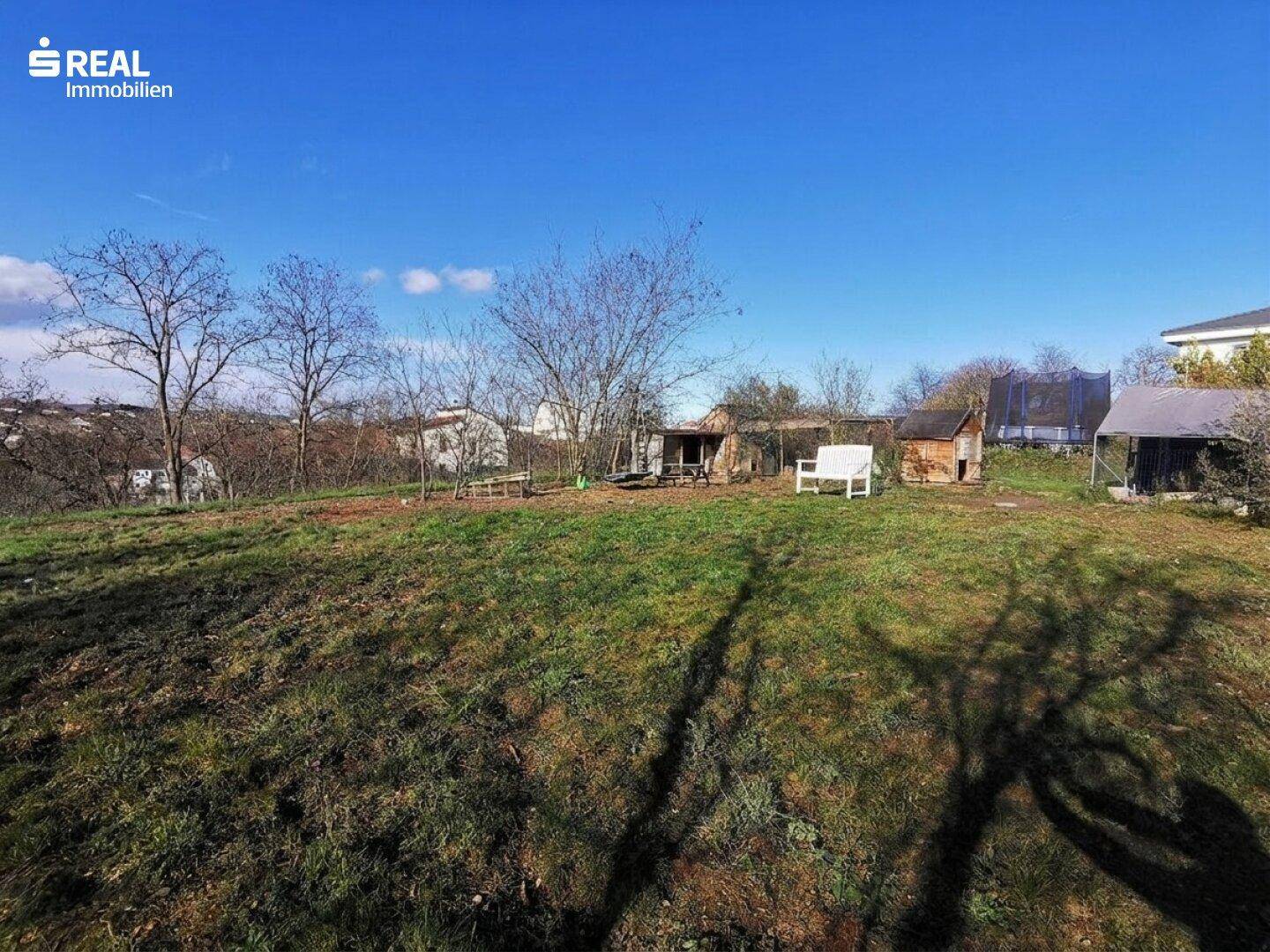 Großes Gartengrundstück mit Sitzgelegenheiten, Schuppen und Blick auf die Umgebung.