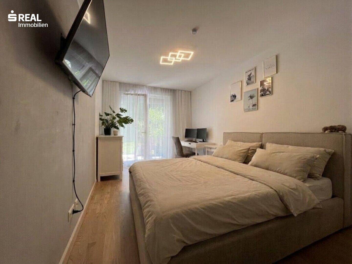 Helles Schlafzimmer mit Doppelbett, Holzboden und Zugang zu einem Außenbereich.