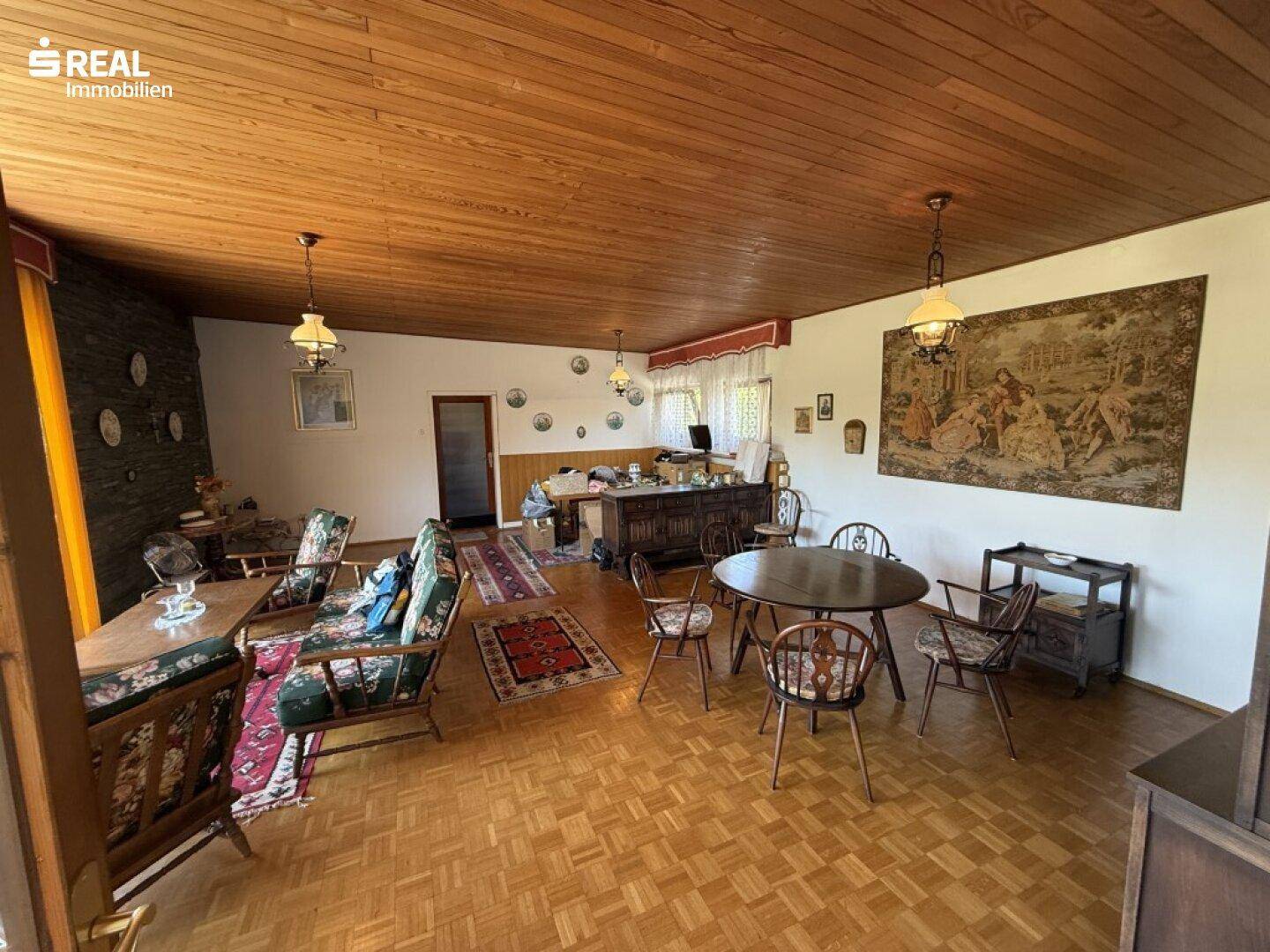 Geräumiger Wohn-Essbereich mit Holzdecke, Parkettboden und traditioneller Einrichtung.
