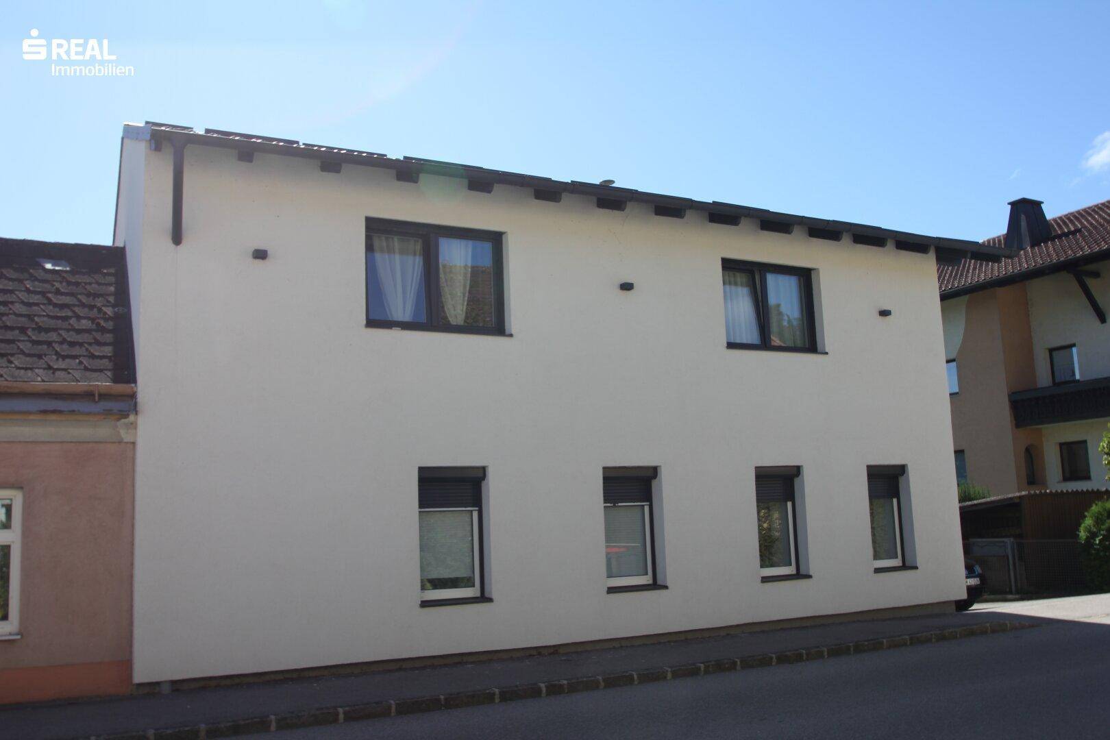 Ansicht des Einfamilienhauses von der Straßenseite mit mehreren Fenstern und heller Fassade.