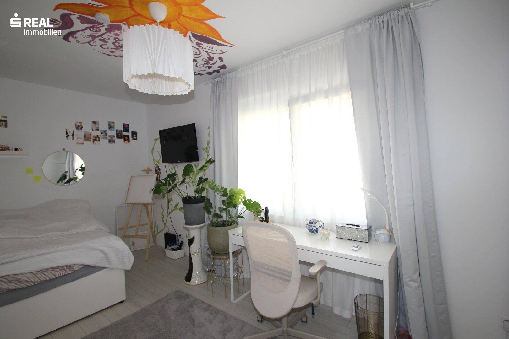 Helles Schlafzimmer mit Schreibtisch, Pflanzen und dekorativer Deckenmalerei.