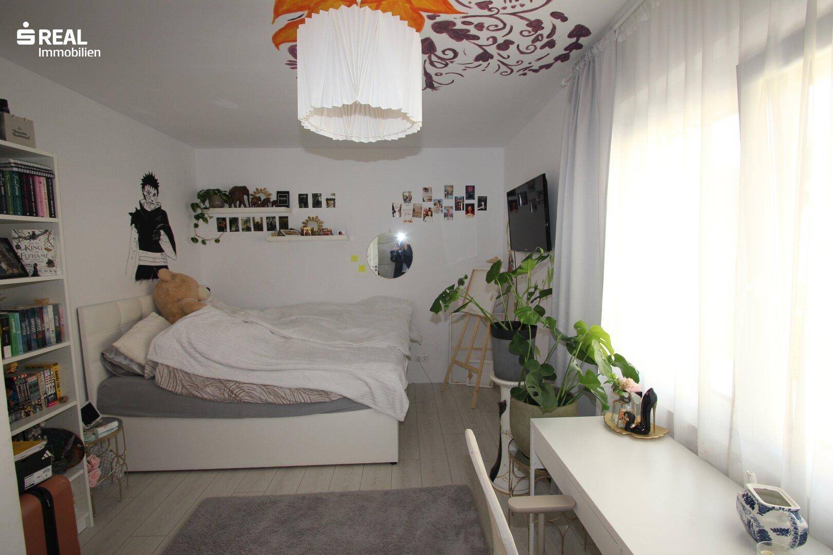 Geräumiges Schlafzimmer mit Bett, Schreibtisch und kreativer Wand- und Deckendekoration.