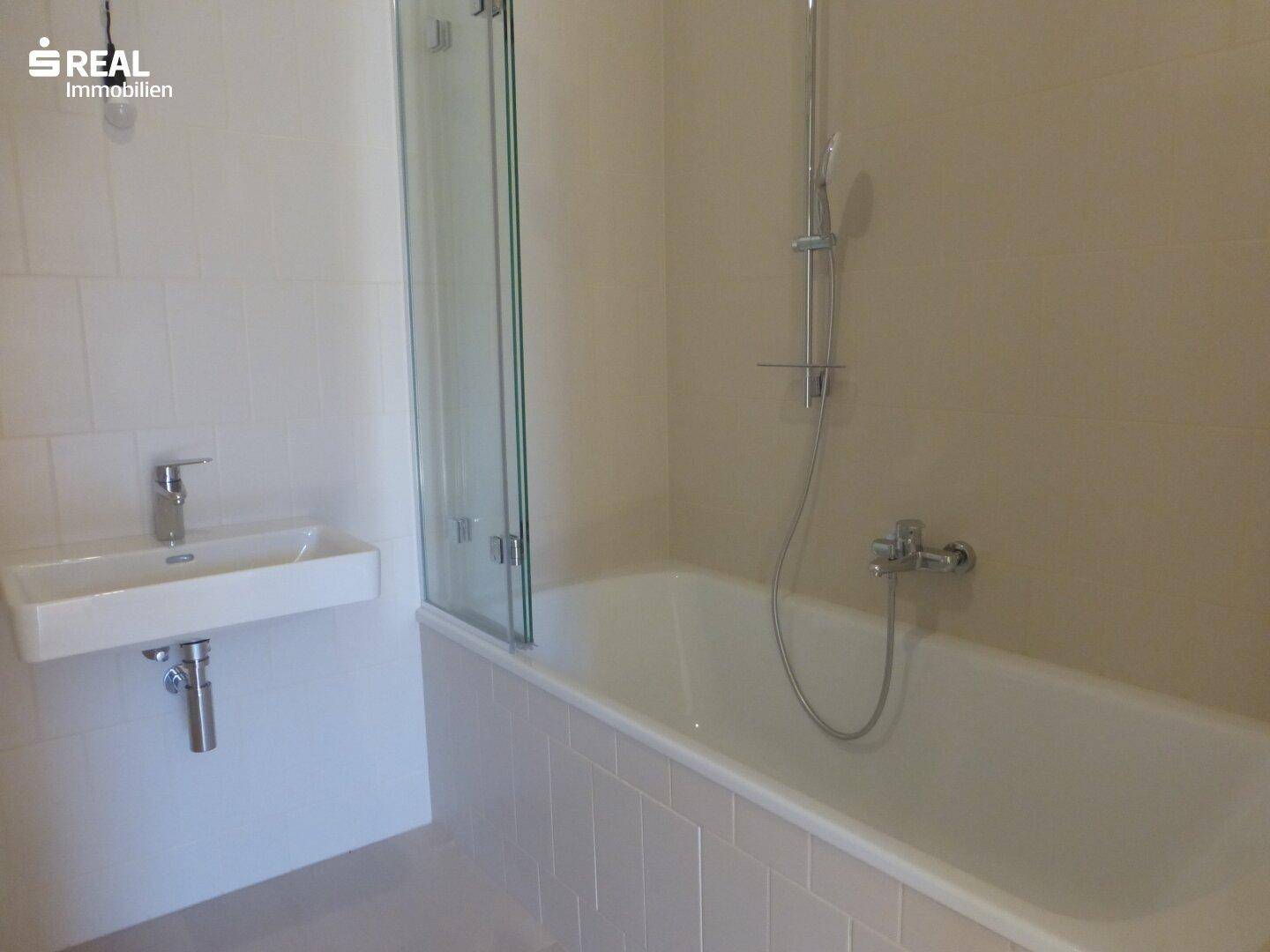Modernes Badezimmer mit Badewanne, Duschabtrennung und Wandwaschbecken.