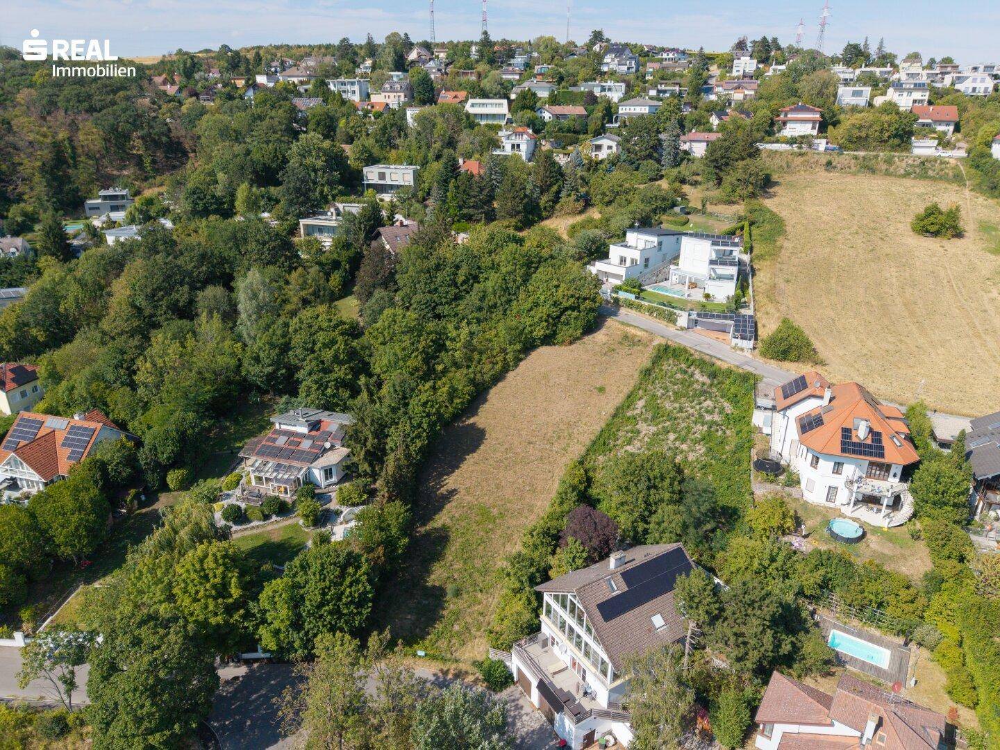 Weitläufige Luftaufnahme eines Baugrundstücks mit Blick auf die umliegende Wohngegend und Pools.