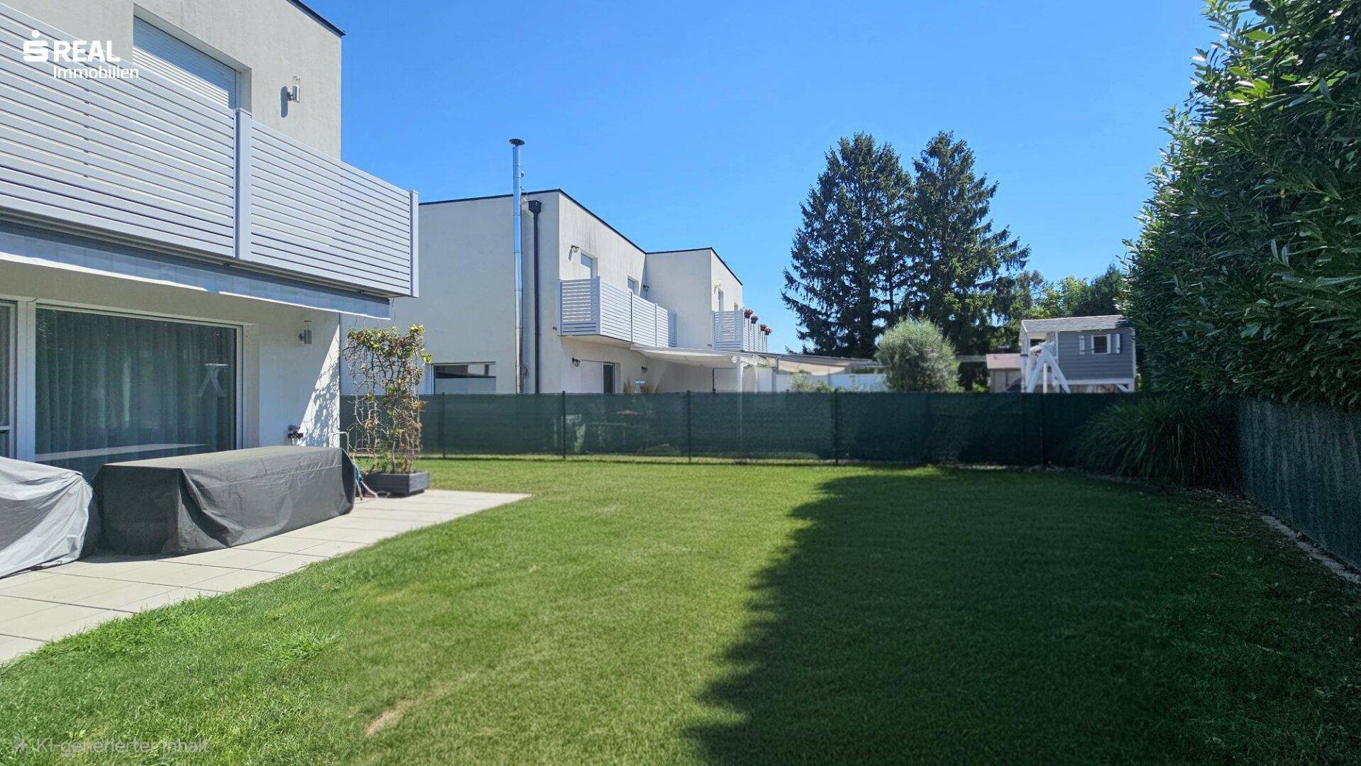 Gepflegter Garten mit Rasenfläche hinter dem modernen Reihenhaus unter blauem Himmel.