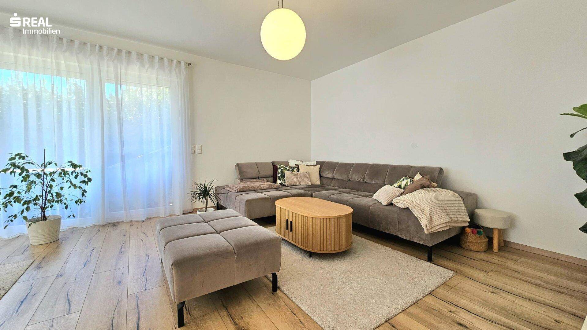 Gemütlicher Wohnbereich mit großem Ecksofa, Couchtisch und hellem Holzboden.