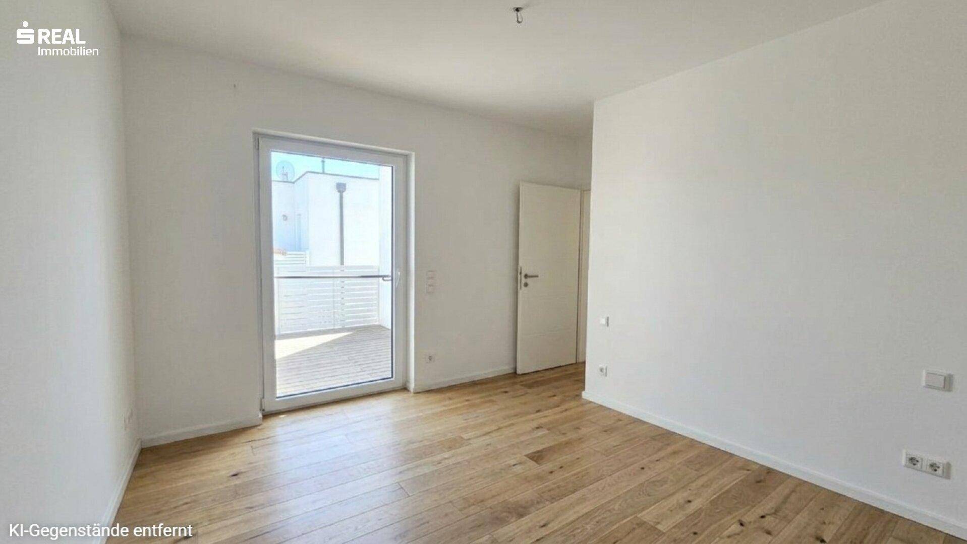 Leerer Raum mit Holzboden und Zugang zu einem Balkon oder einer Terrasse.