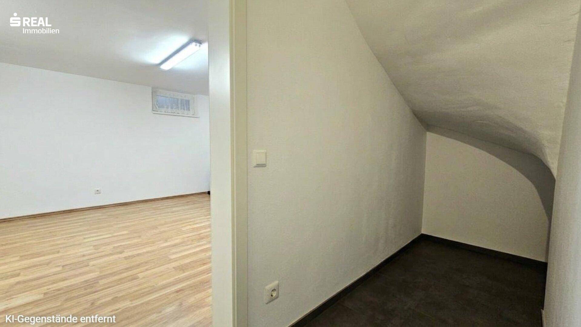 Praktischer Abstellraum unter der Treppe mit dunklem Boden und weiß gestrichenen Wänden.
