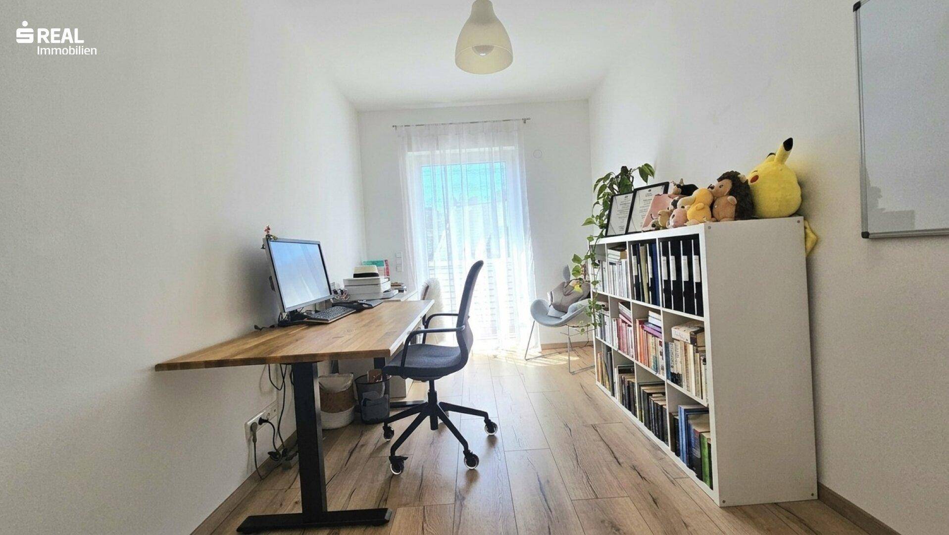 Helles Arbeitszimmer mit Schreibtisch, Bücherregal und Zugang zu einem Außenbereich.
