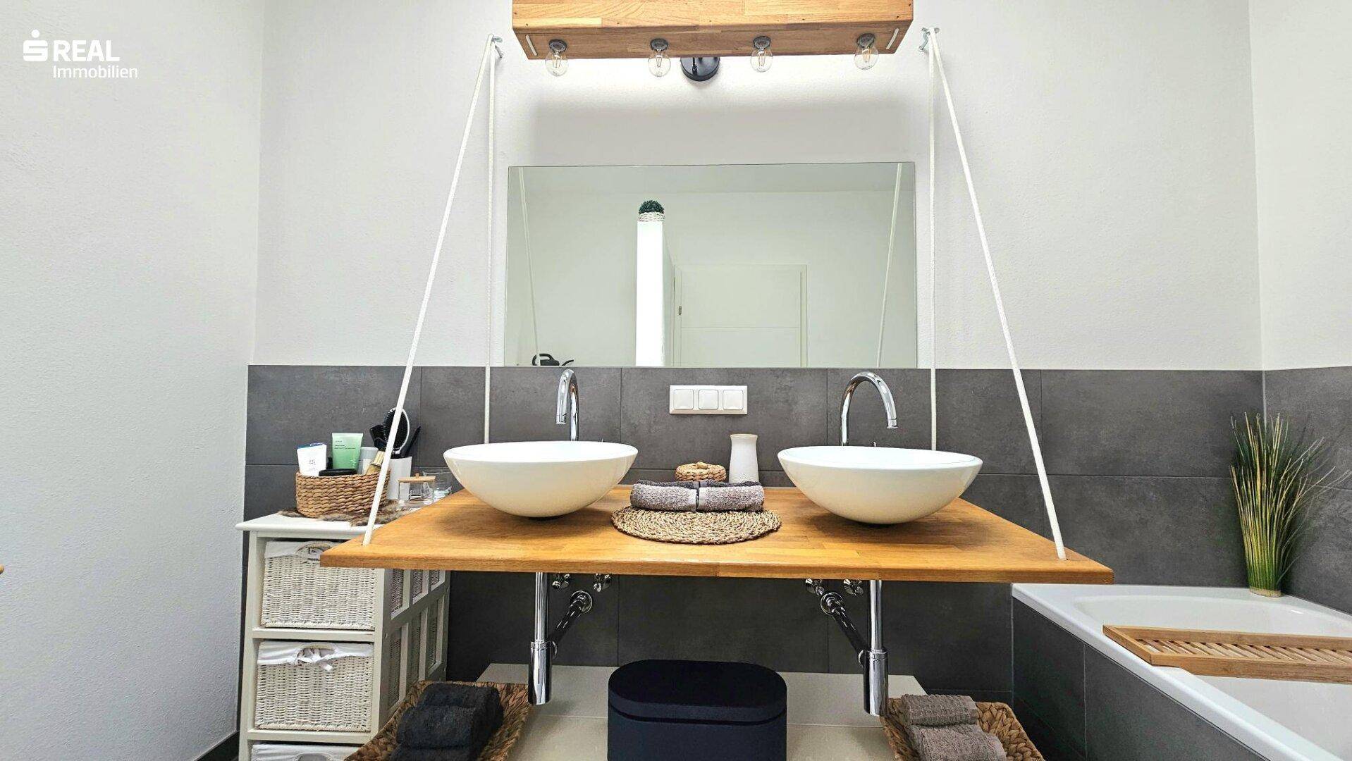 Stilvolles Badezimmer mit zwei Aufsatzwaschbecken, großem Spiegel und Badewanne.