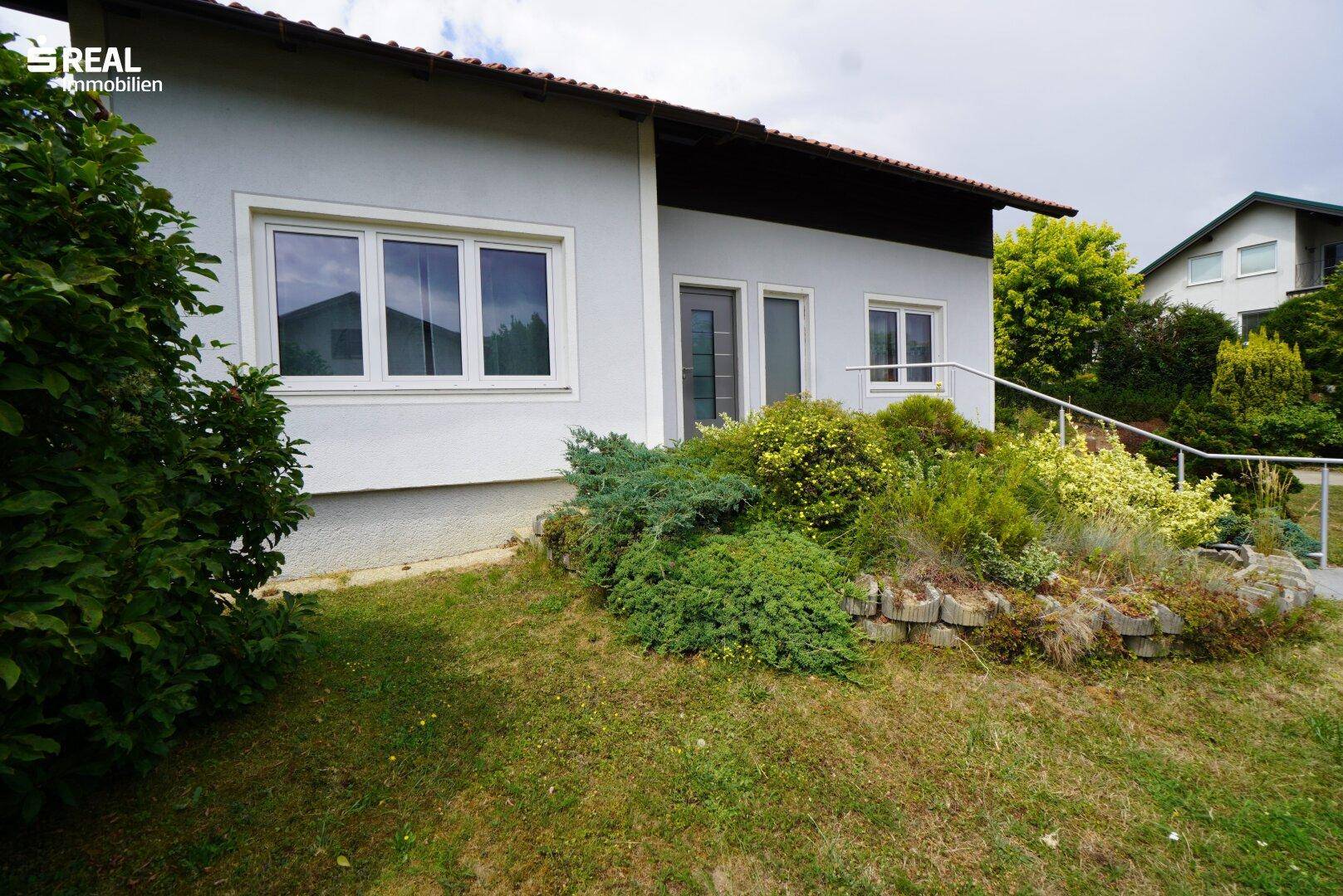Seitenansicht des Hauses mit Fenstern und üppiger Bepflanzung im Gartenbereich.