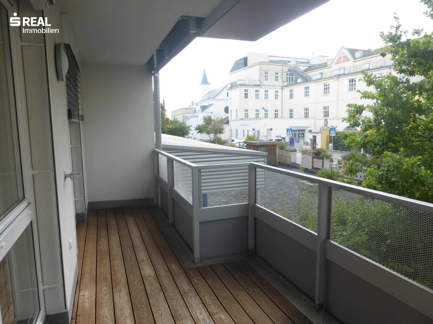 Balkon mit Holzboden und Blick auf die Straße mit historischen Gebäuden.
