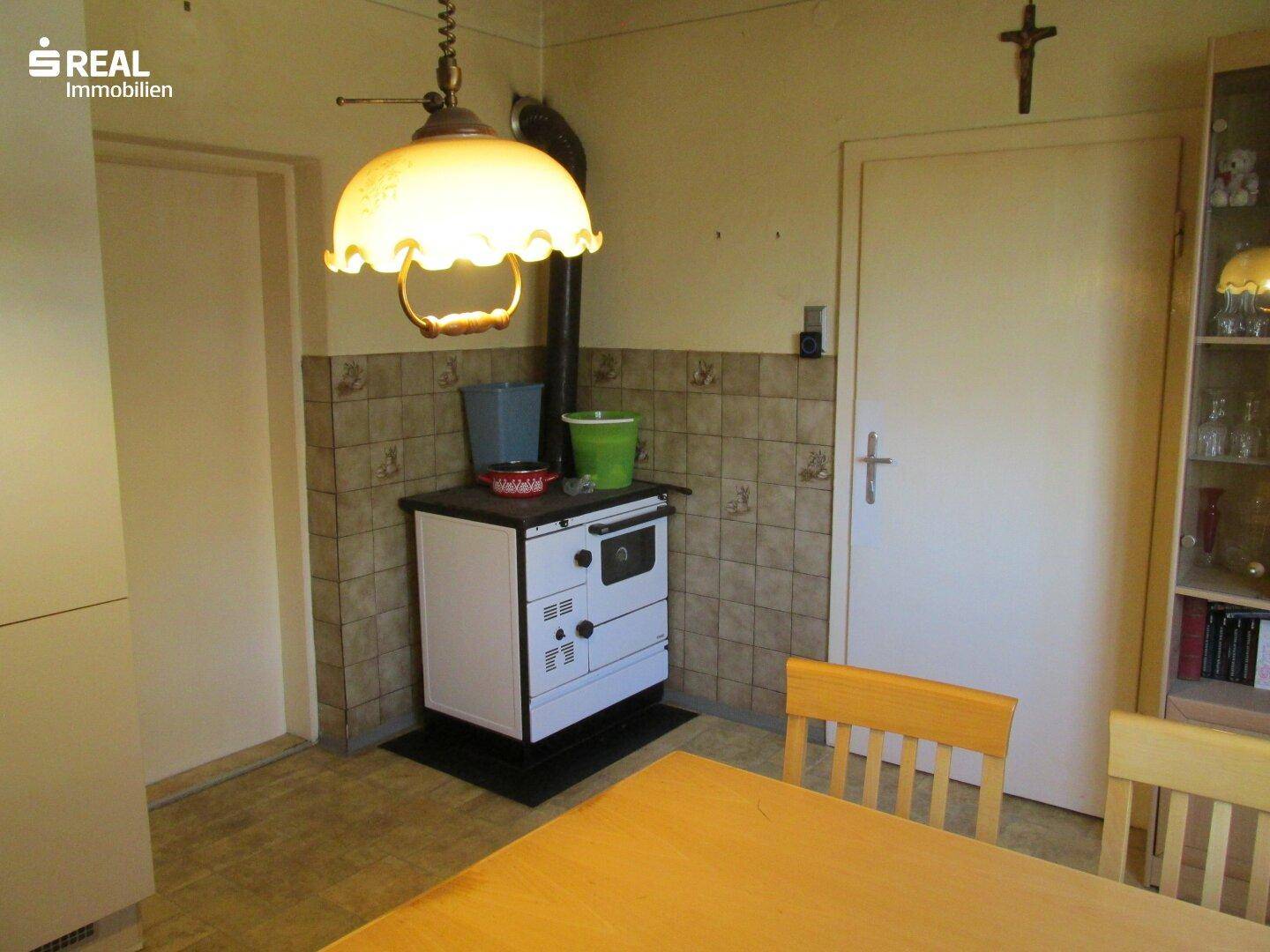 Gemütliche Küche mit Esstisch, traditionellem Holzofen und gefliestem Spritzschutz.