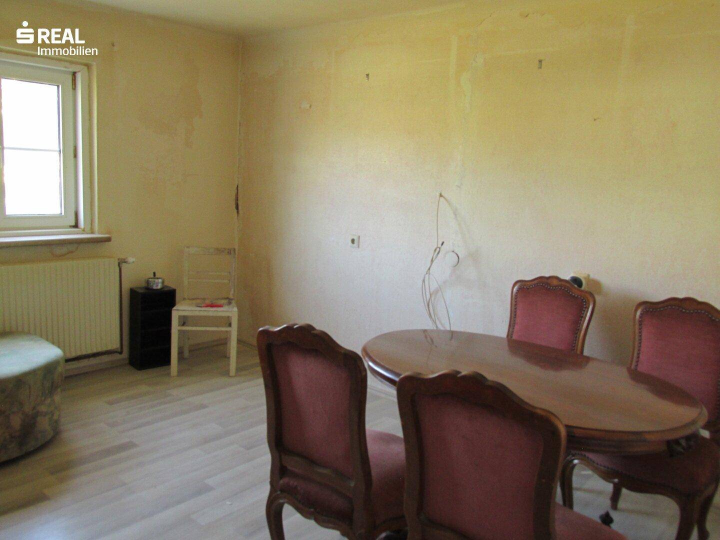Essbereich mit Holztisch, Stühlen und einem Fenster, das viel natürliches Licht hereinlässt.