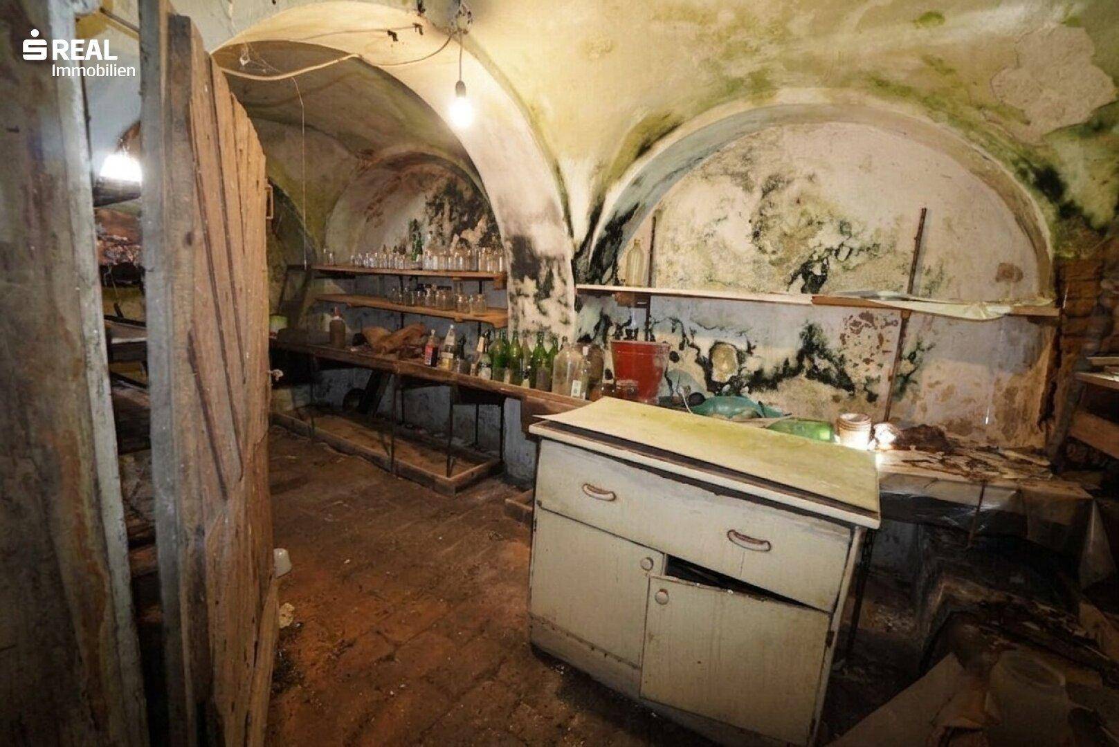 Historischer Weinkeller mit Steingewölbe, Regalen und alten Flaschen.