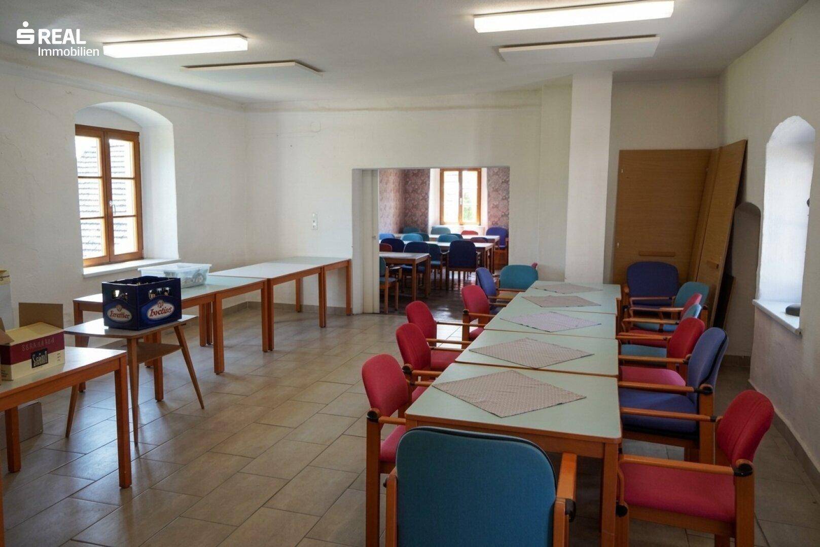 Geräumiger Essbereich mit mehreren Tischen und Stühlen, ideal für Versammlungen oder Veranstaltungen.