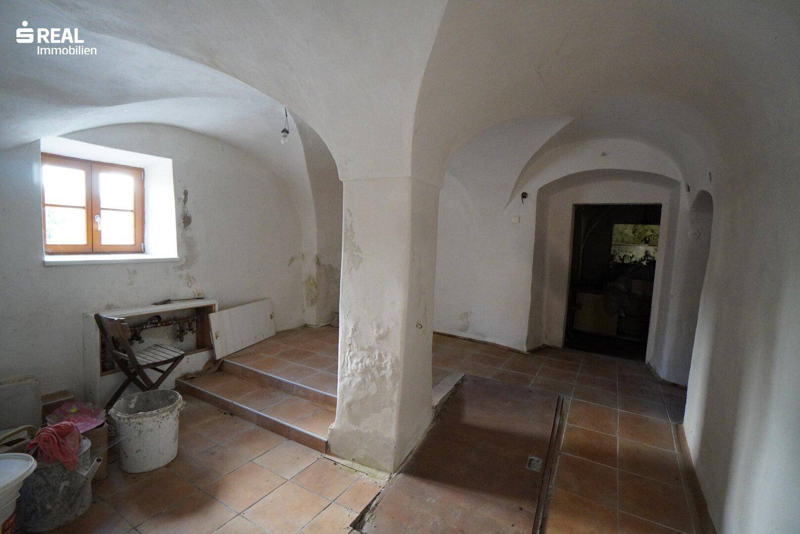 Historischer Raum mit Gewölbedecken, Säulen und Terrakotta-Fliesenboden.