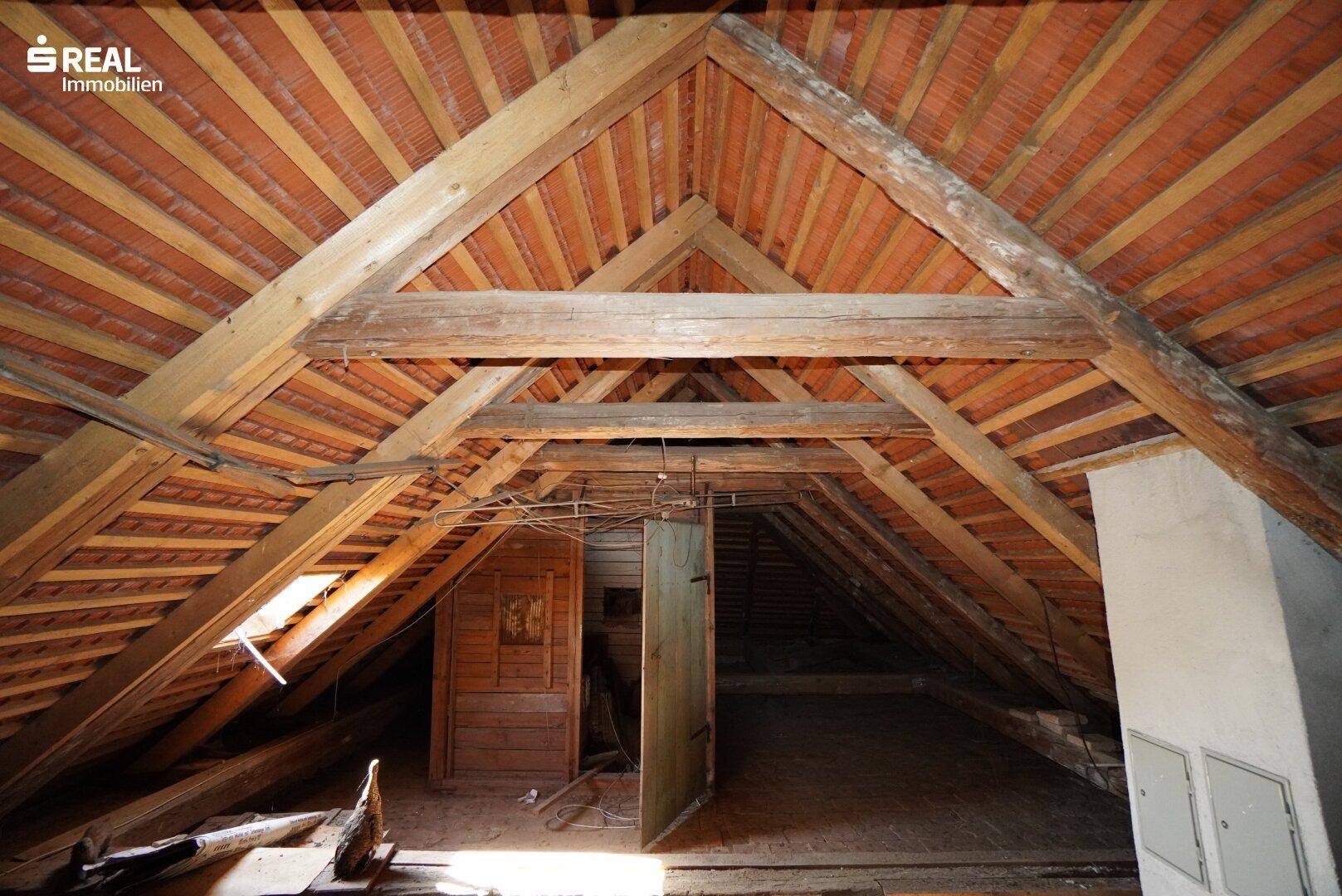 Dachboden mit sichtbarer Holzkonstruktion und Ziegeln, bietet Ausbaupotenzial.