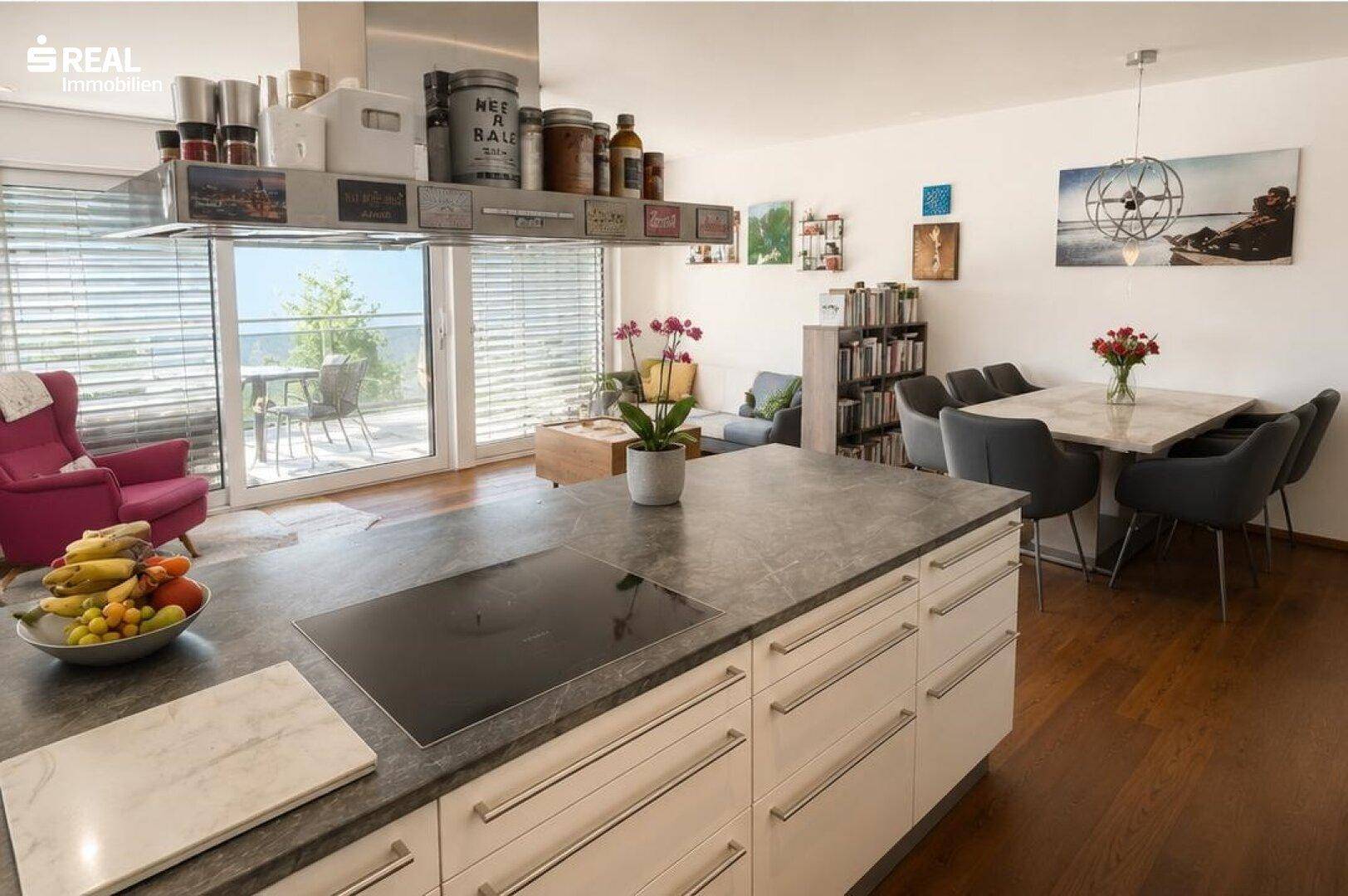 Heller offener Wohnbereich mit moderner Küche, Essbereich und Zugang zum sonnigen Balkon.
