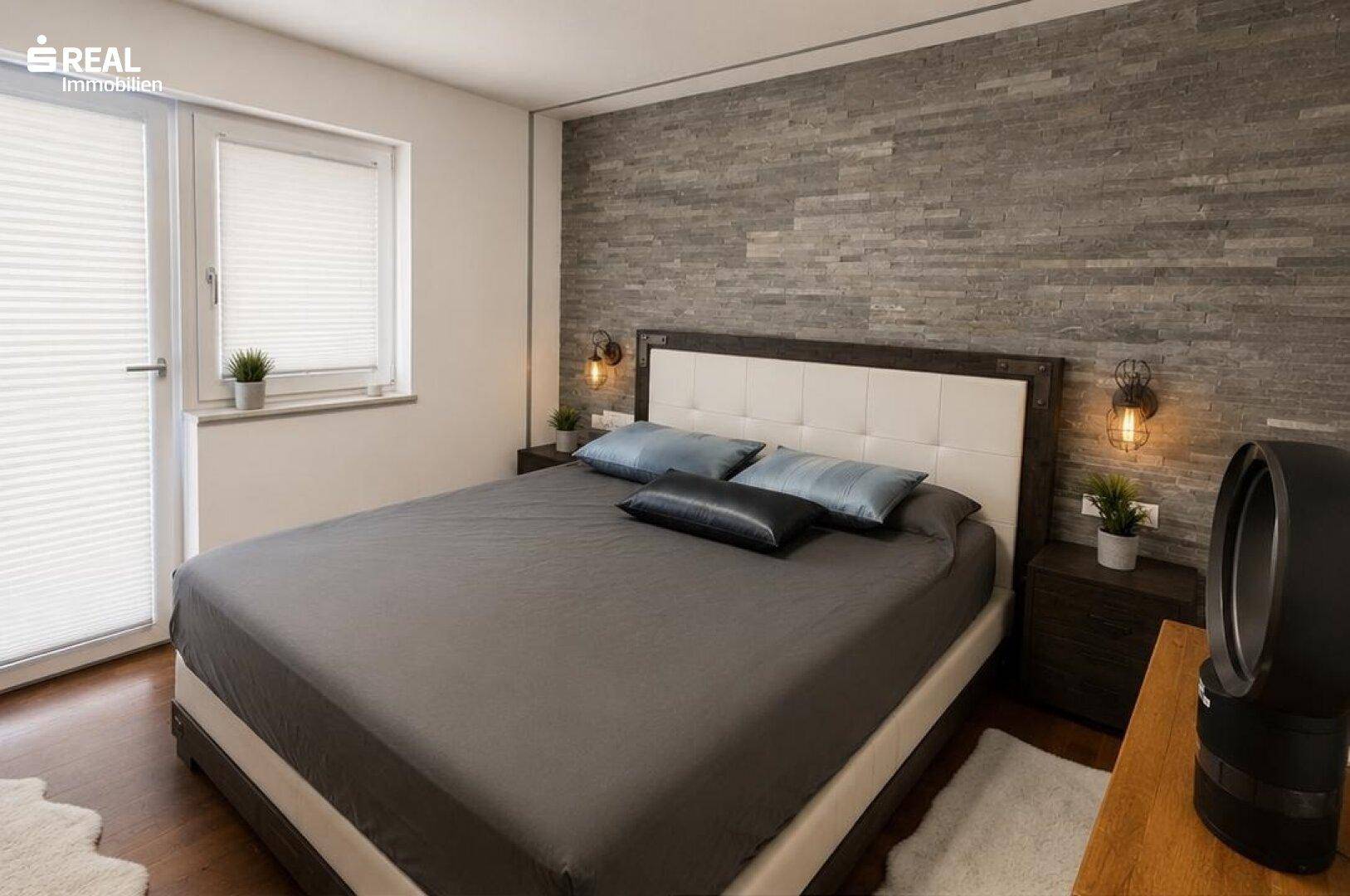 Gemütliches Schlafzimmer mit Doppelbett, Nachttischen und einer dekorativen Steinwand.
