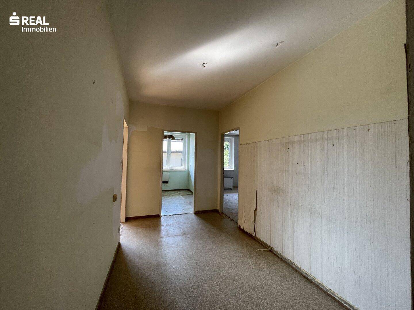 Heller Flur mit älteren Tapeten und Zugang zu mehreren Zimmern der Wohnung.