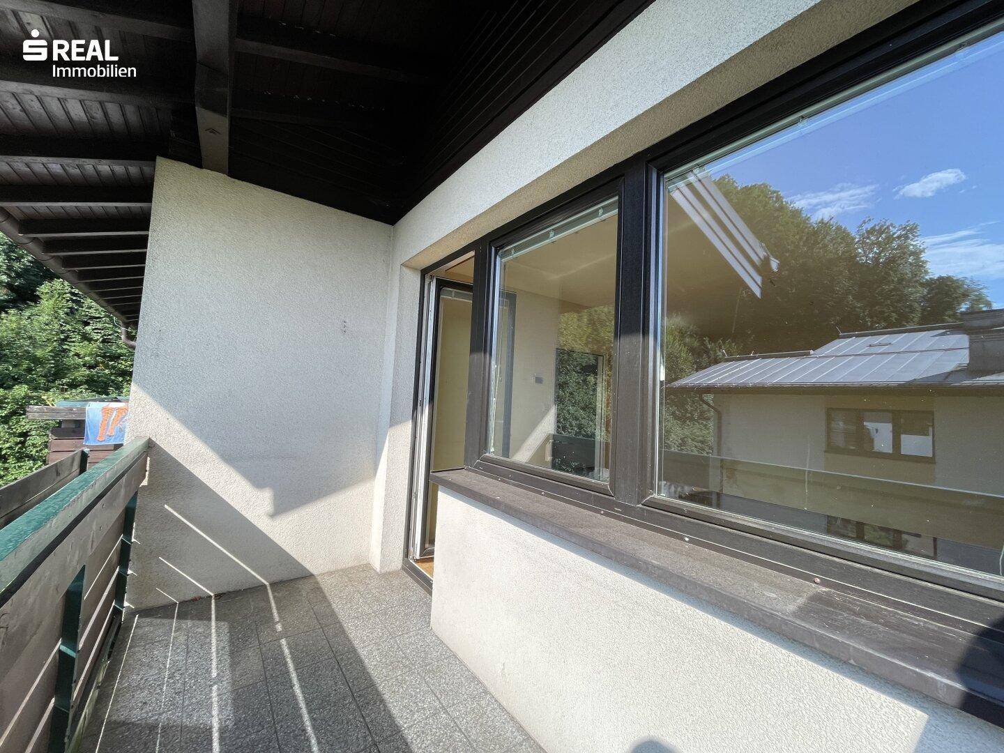 Überdachter Balkon mit Fliesenboden und Blick ins Grüne, ideal für entspannte Stunden.