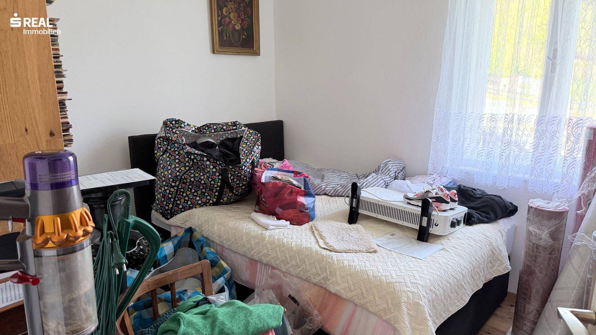 Schlafzimmer mit Bett und Fenster, das viel Tageslicht hereinlässt.