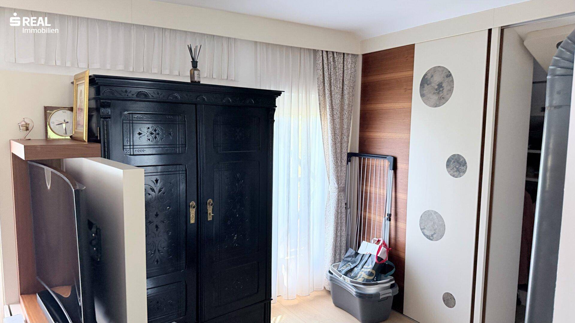 Schlafzimmer mit großem schwarzen Kleiderschrank und modernen Schiebetürenschränken.