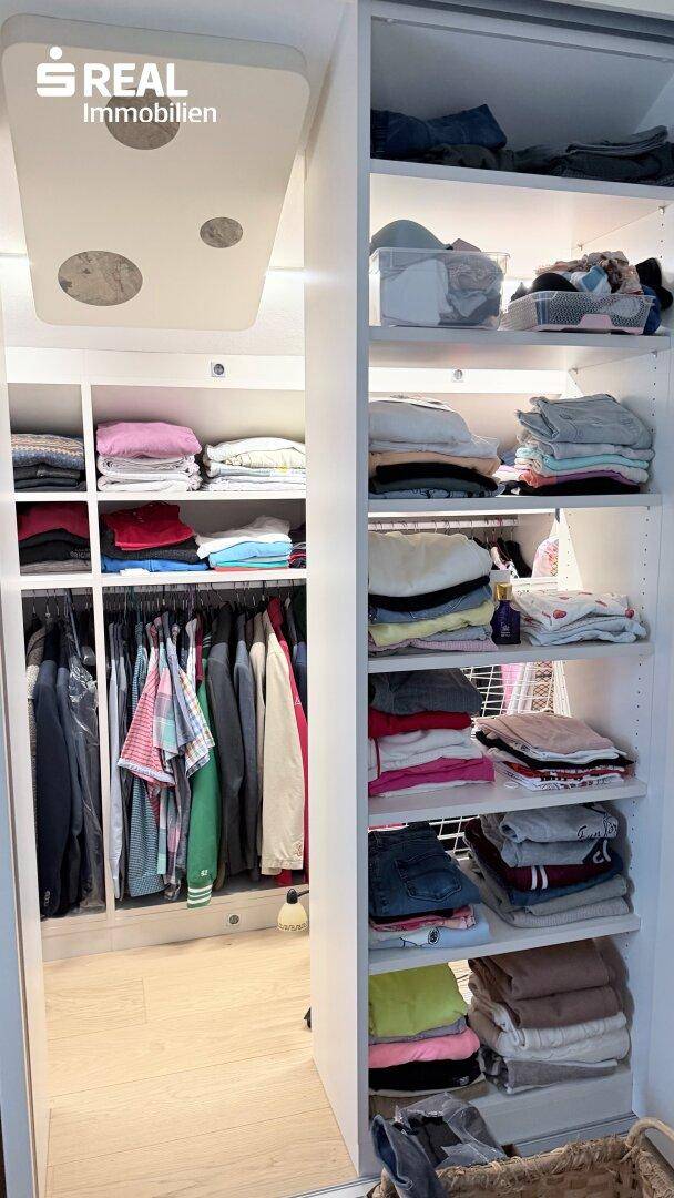 Begehbarer Kleiderschrank mit Regalen und Hängemöglichkeiten für Kleidung.