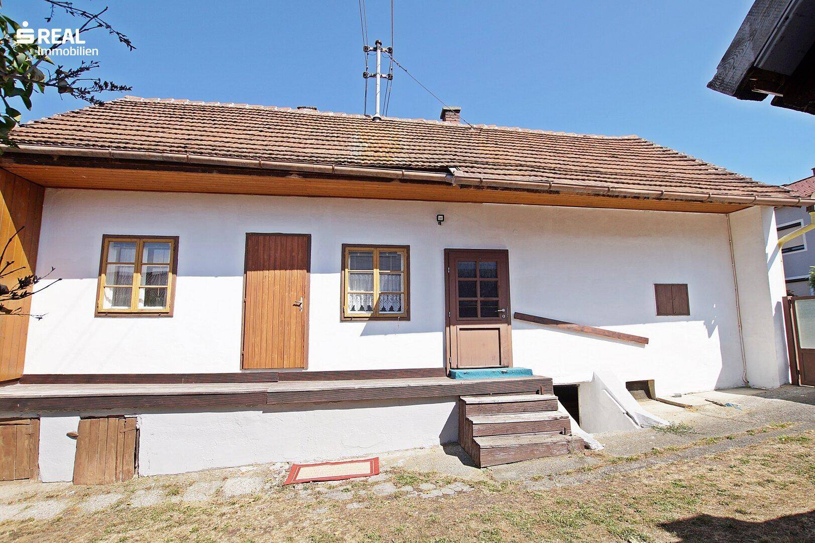 Traditionelles Landhaus mit weißer Fassade, Holztüren und Ziegeldach.