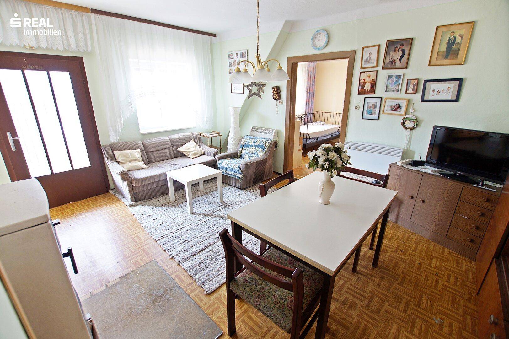 Heller Wohn-Essbereich mit Sofa, Esstisch und Zugang zu einem Außenbereich.