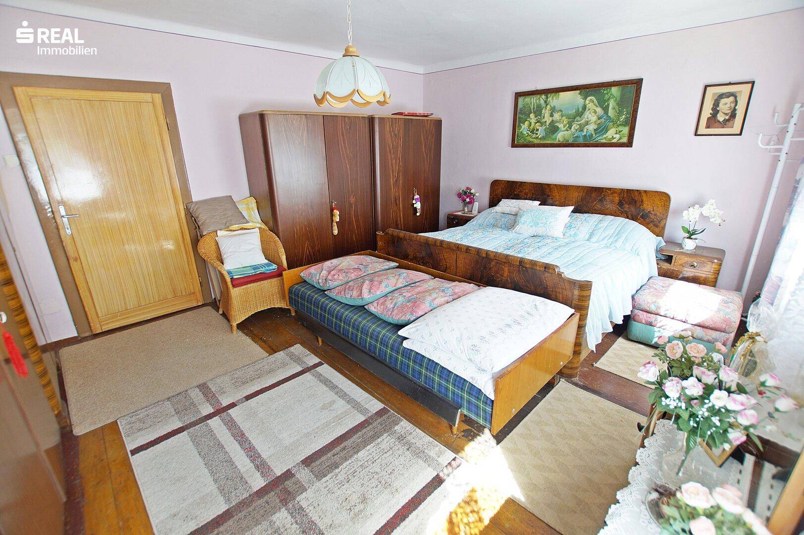 Gemütliches Schlafzimmer mit Doppelbett, Tagesbett und traditionellen Holzmöbeln.
