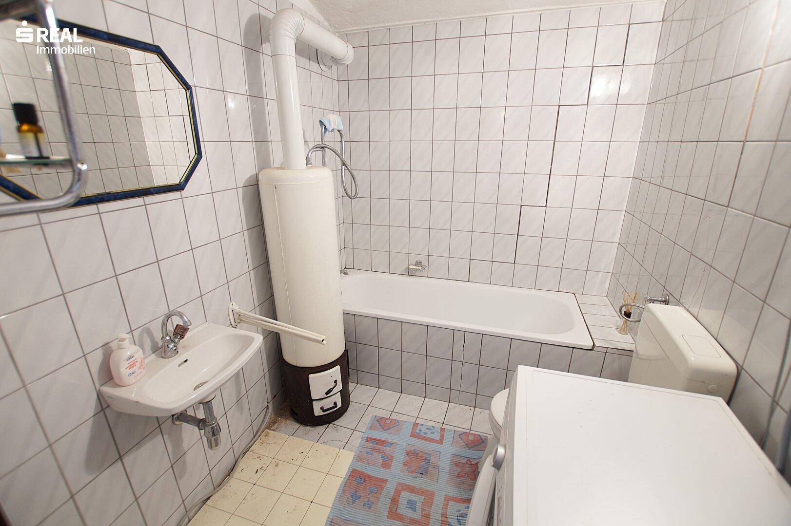 Badezimmer mit Badewanne, Waschbecken und Fliesen an den Wänden.