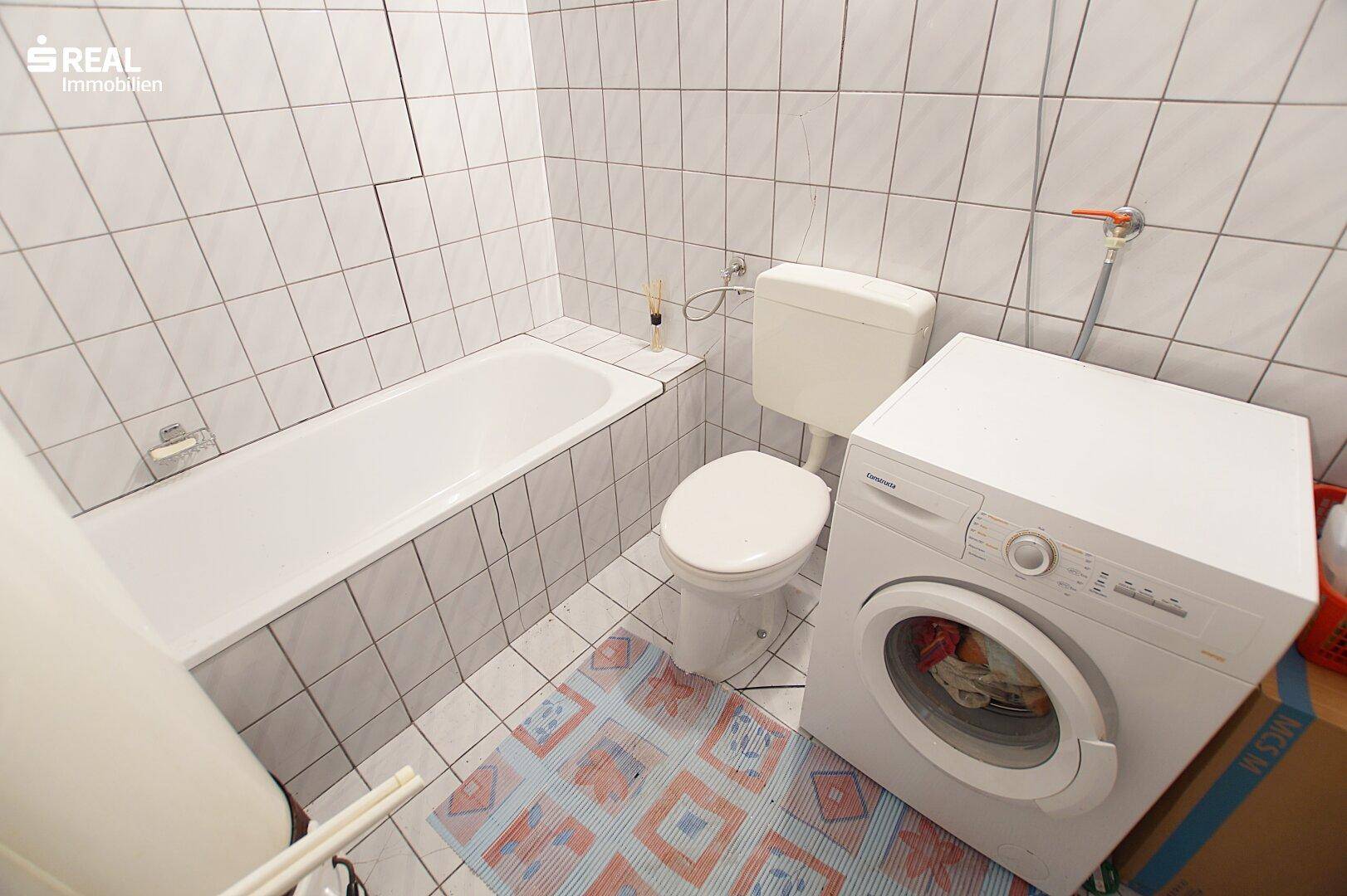 Badezimmer mit Badewanne, Toilette und Waschmaschine.
