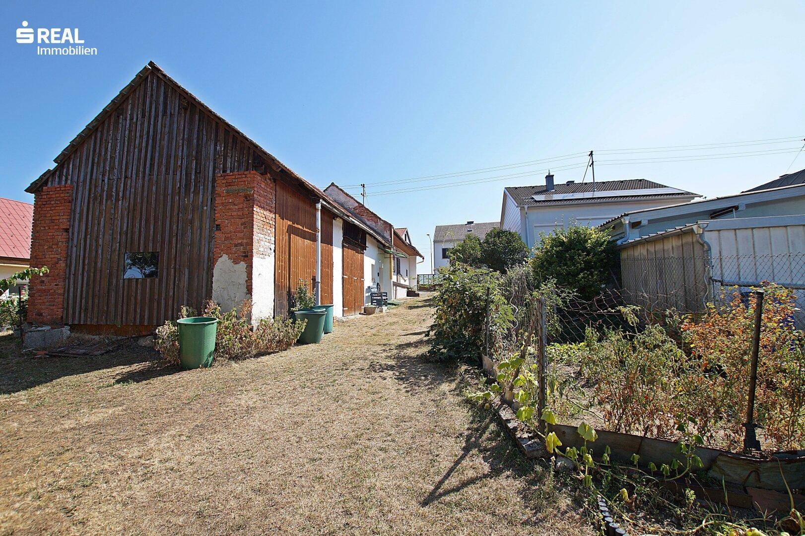 Gartenbereich mit alter Scheune, Zaun und Blick auf die Nachbarschaft.