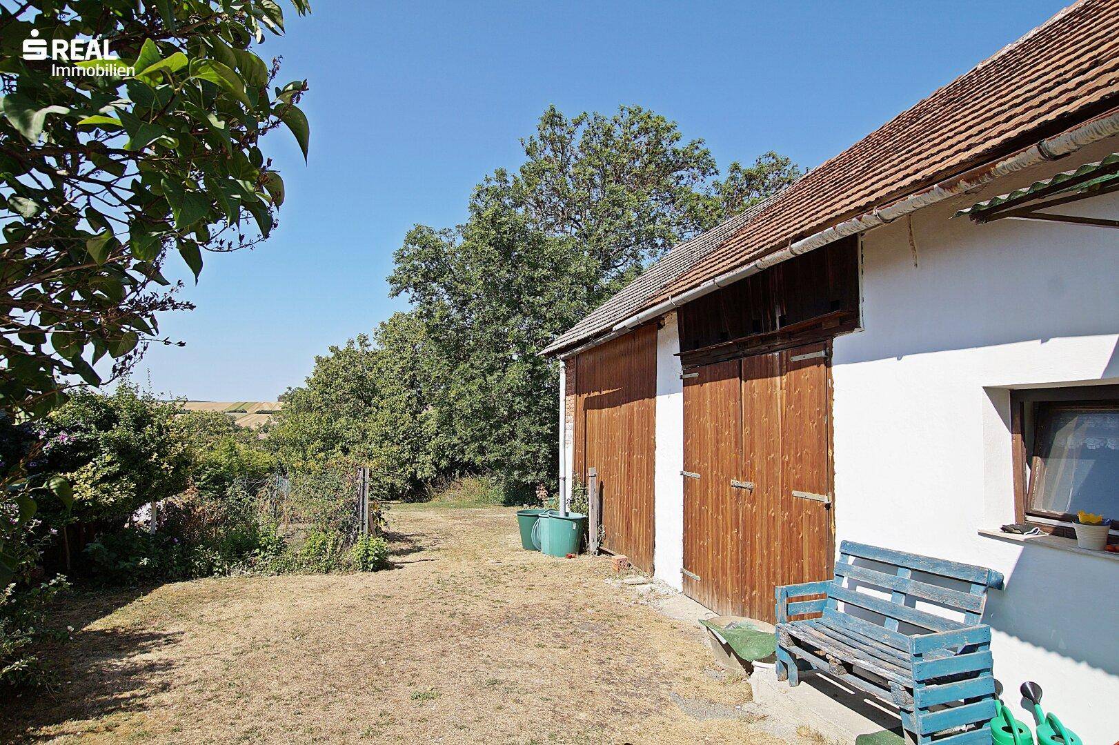 Scheune mit Holztoren und Blick auf die umliegende Landschaft.