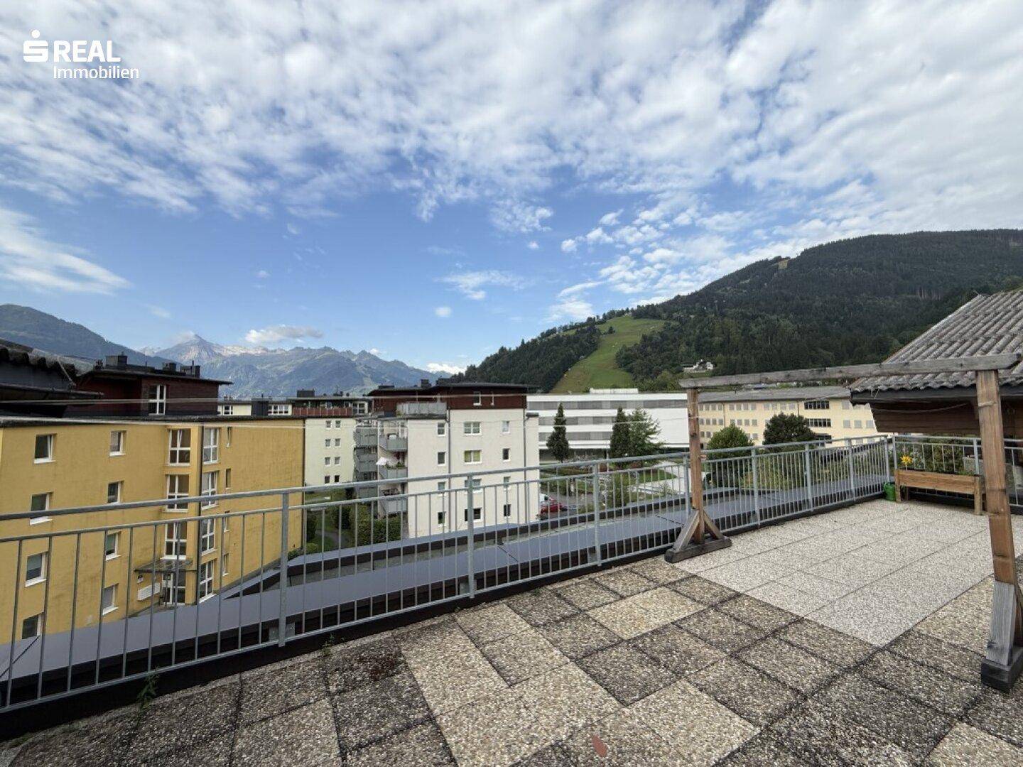 Große Dachterrasse mit weitem Blick auf die umliegende Berglandschaft und Gebäude.