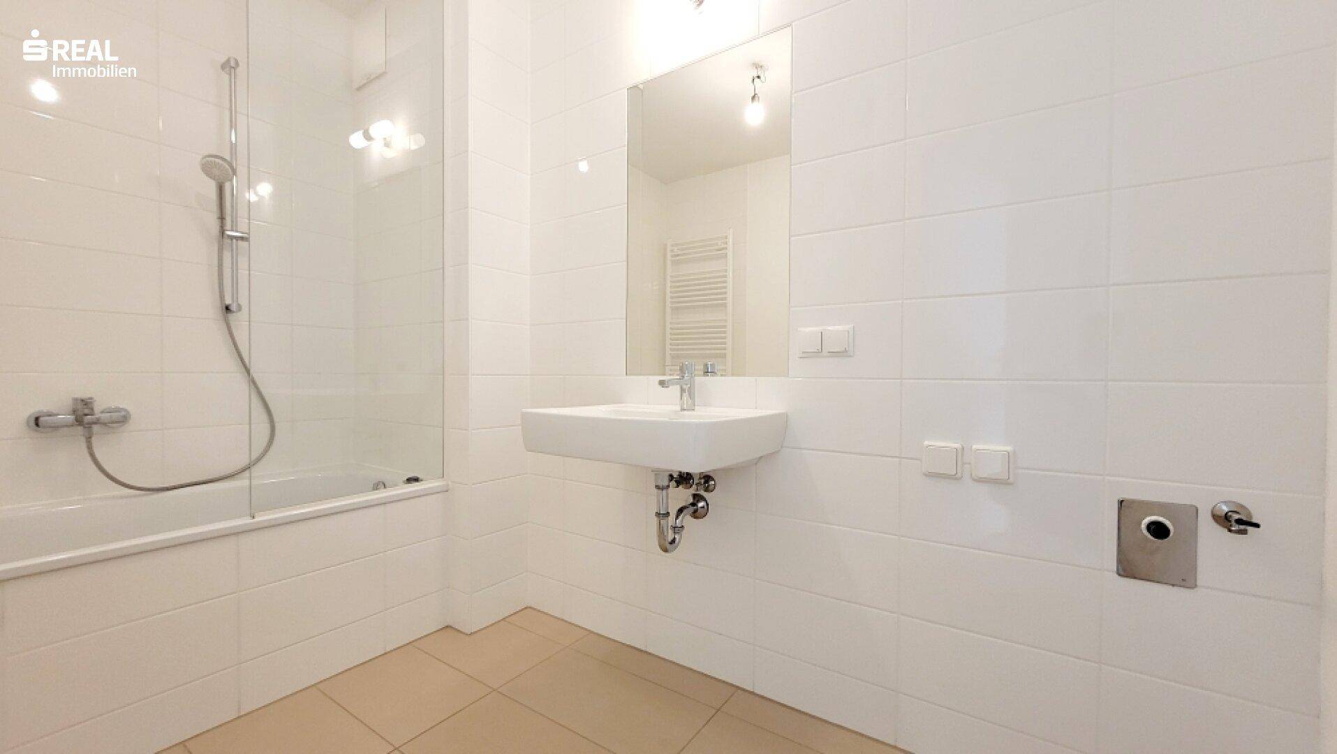 Modernes Badezimmer mit Badewanne, Dusche und beheiztem Handtuchhalter.