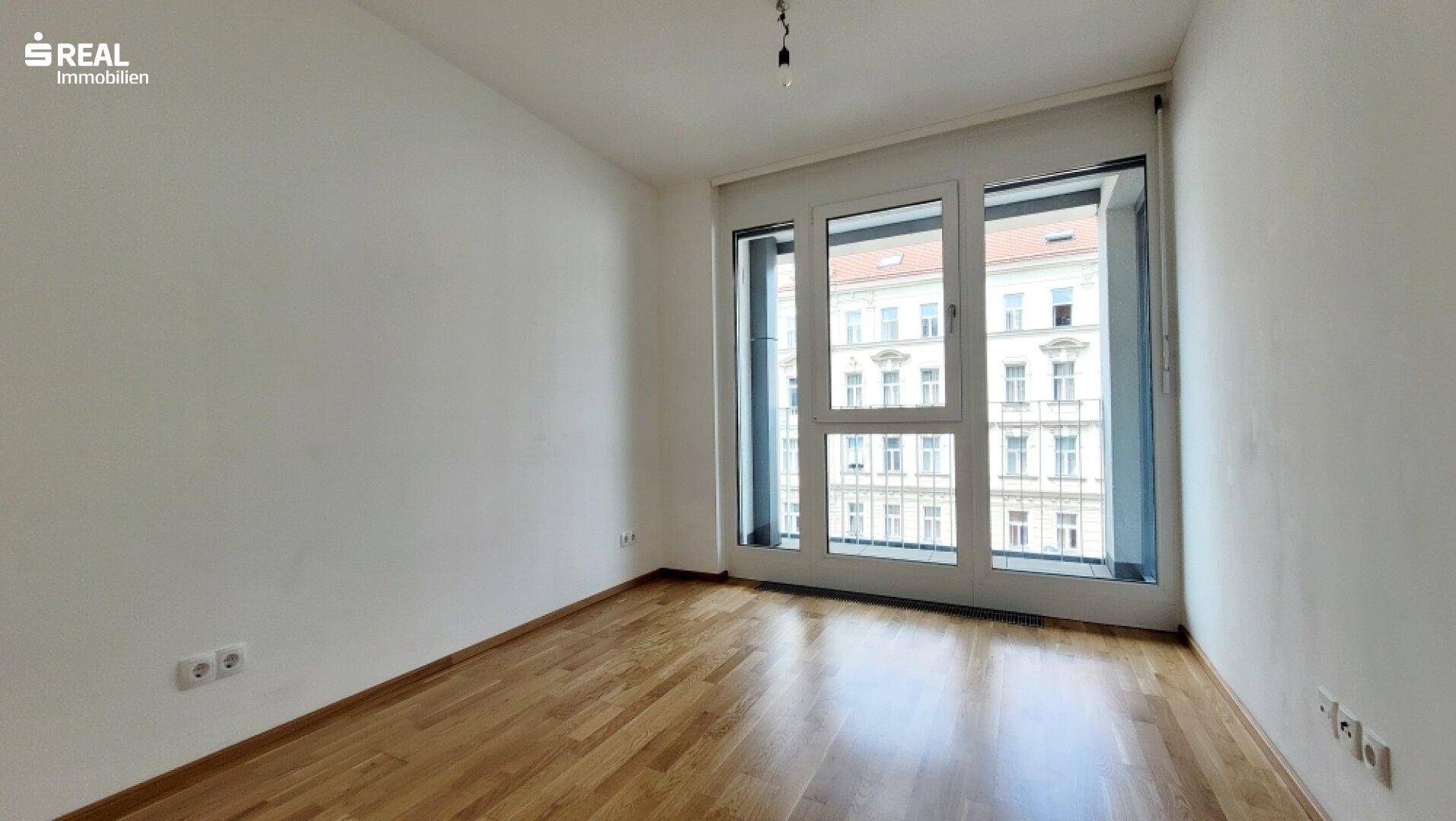 Helles Schlafzimmer mit Parkettboden und französischem Balkon.